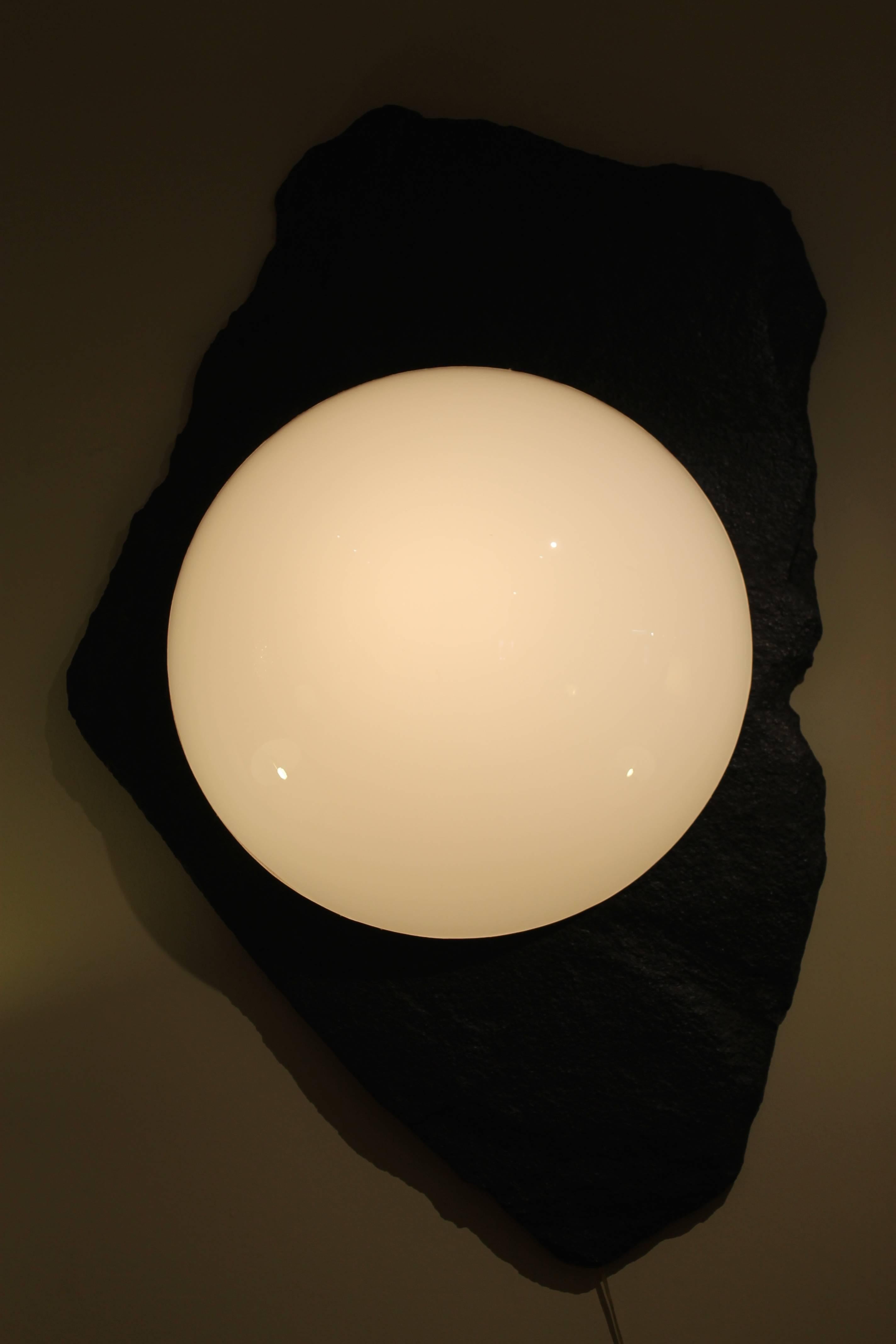 A massive and striking wall light featuring a white plexiglass bubble protruding from a giant slab of fiberglass 