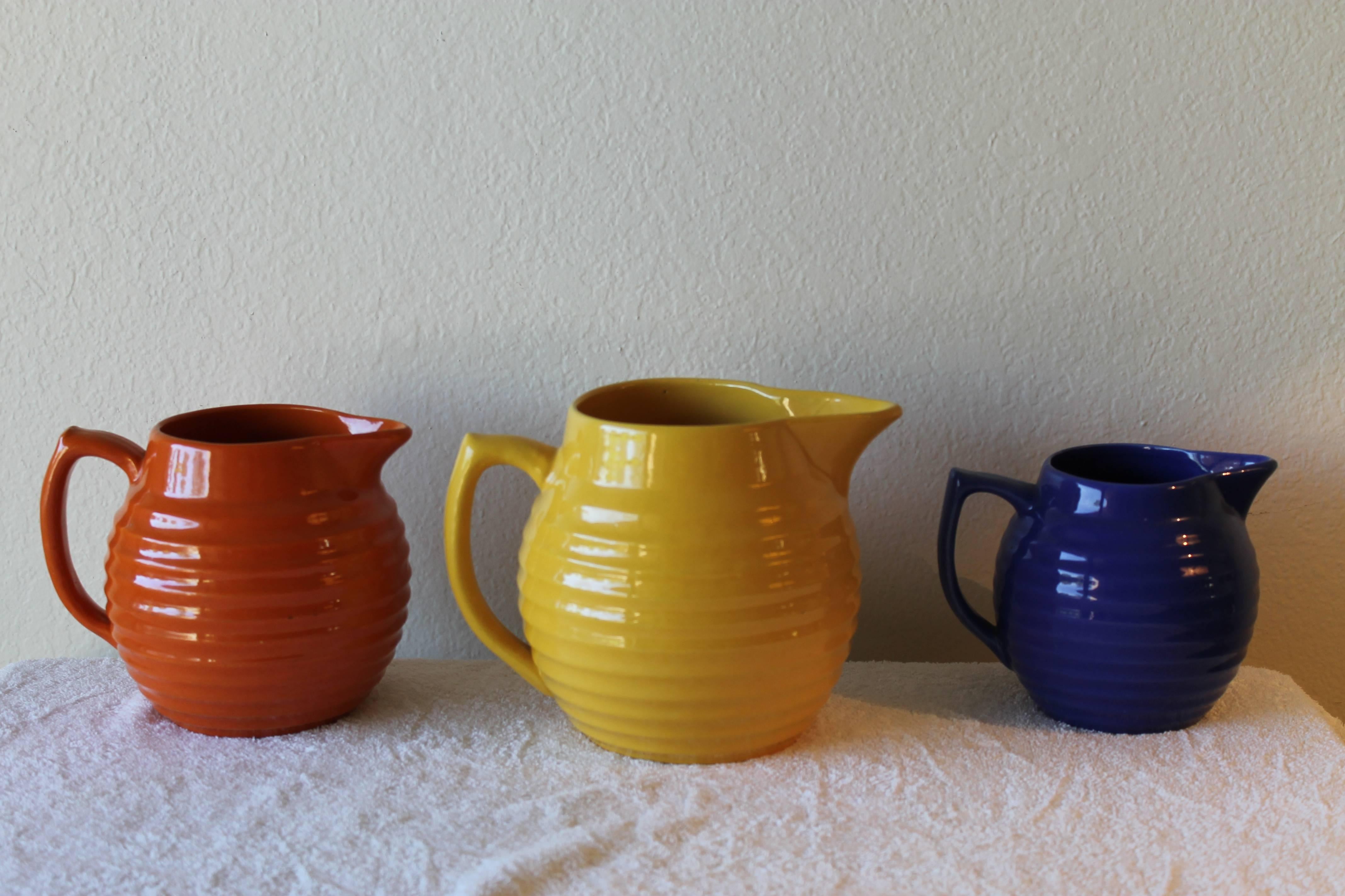 Set of Bauer graduated pitchers in 5 colors.  Colors are yellow, red/orange, cobalt, jade green and burgundy. 
