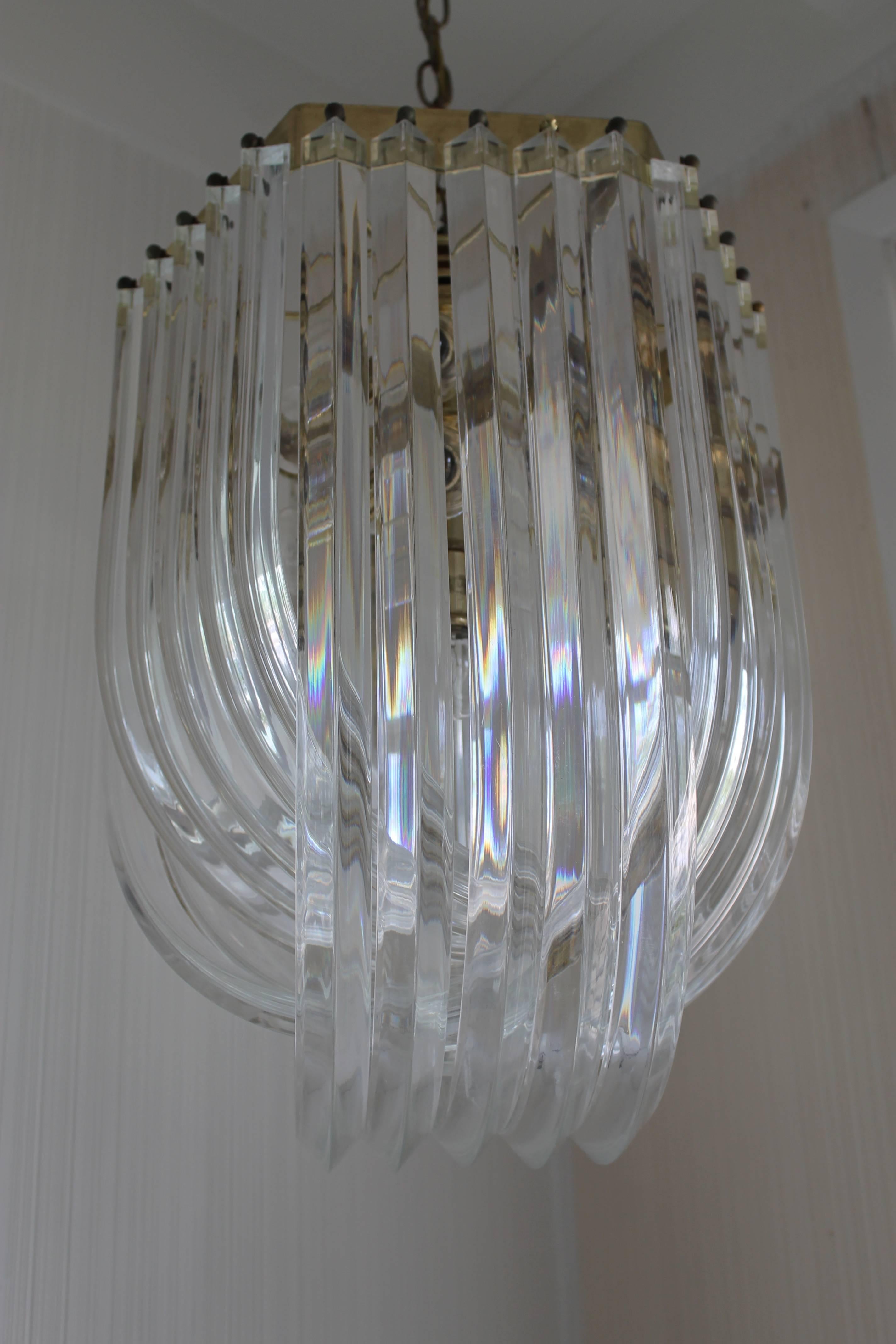 A chandelier, circa 1970s featuring U-shaped ridged bands of clear Lucite intertwining in three groups of five. Measures: The chandelier measures 20