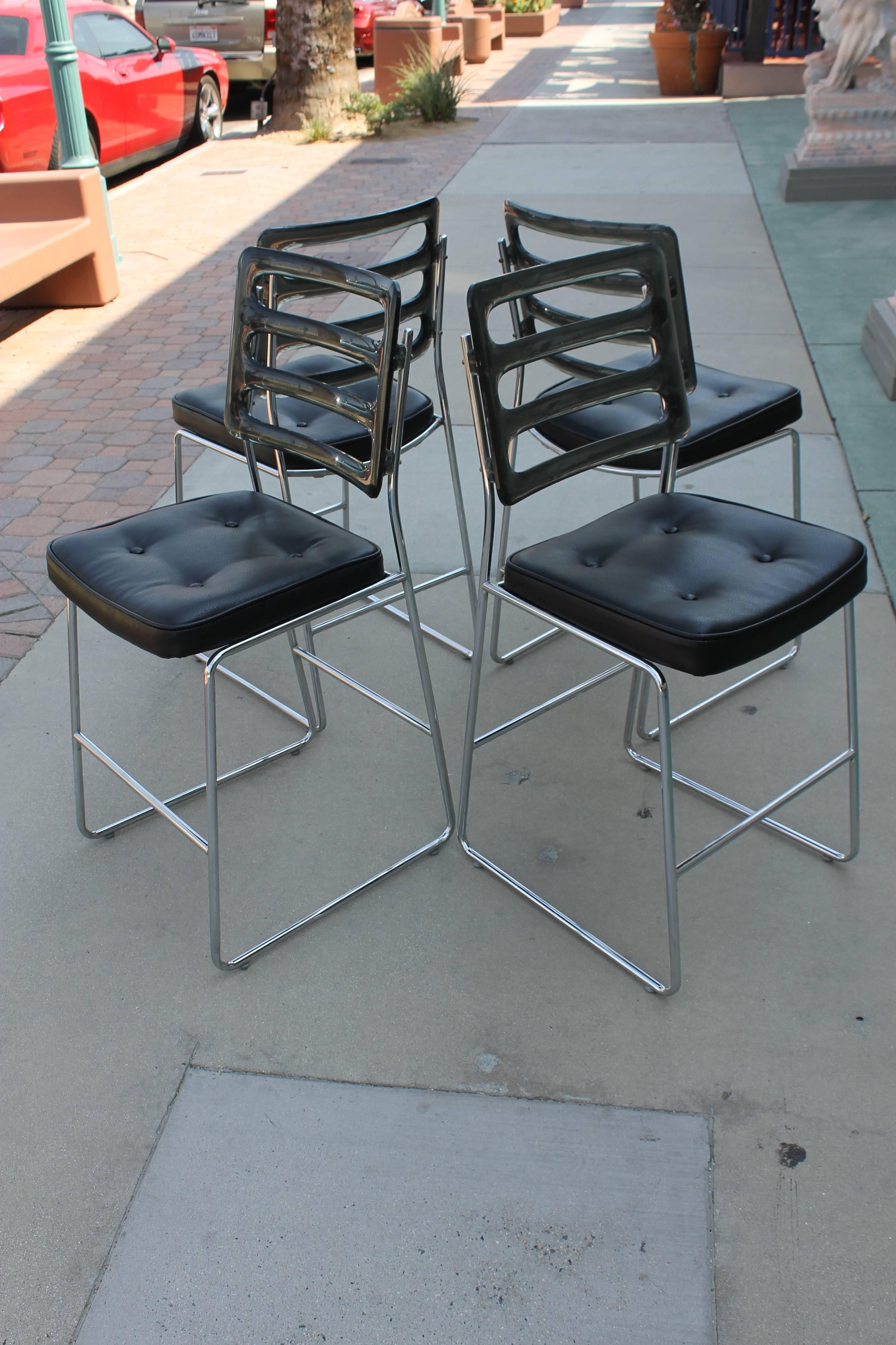 Four matching bar stools by Chromcraft, with cast acrylic seat backs and chromed steel frames. Seats are newly reupholstered in black faux leather. Cast acrylic backs are clear smoke color. These measure 40