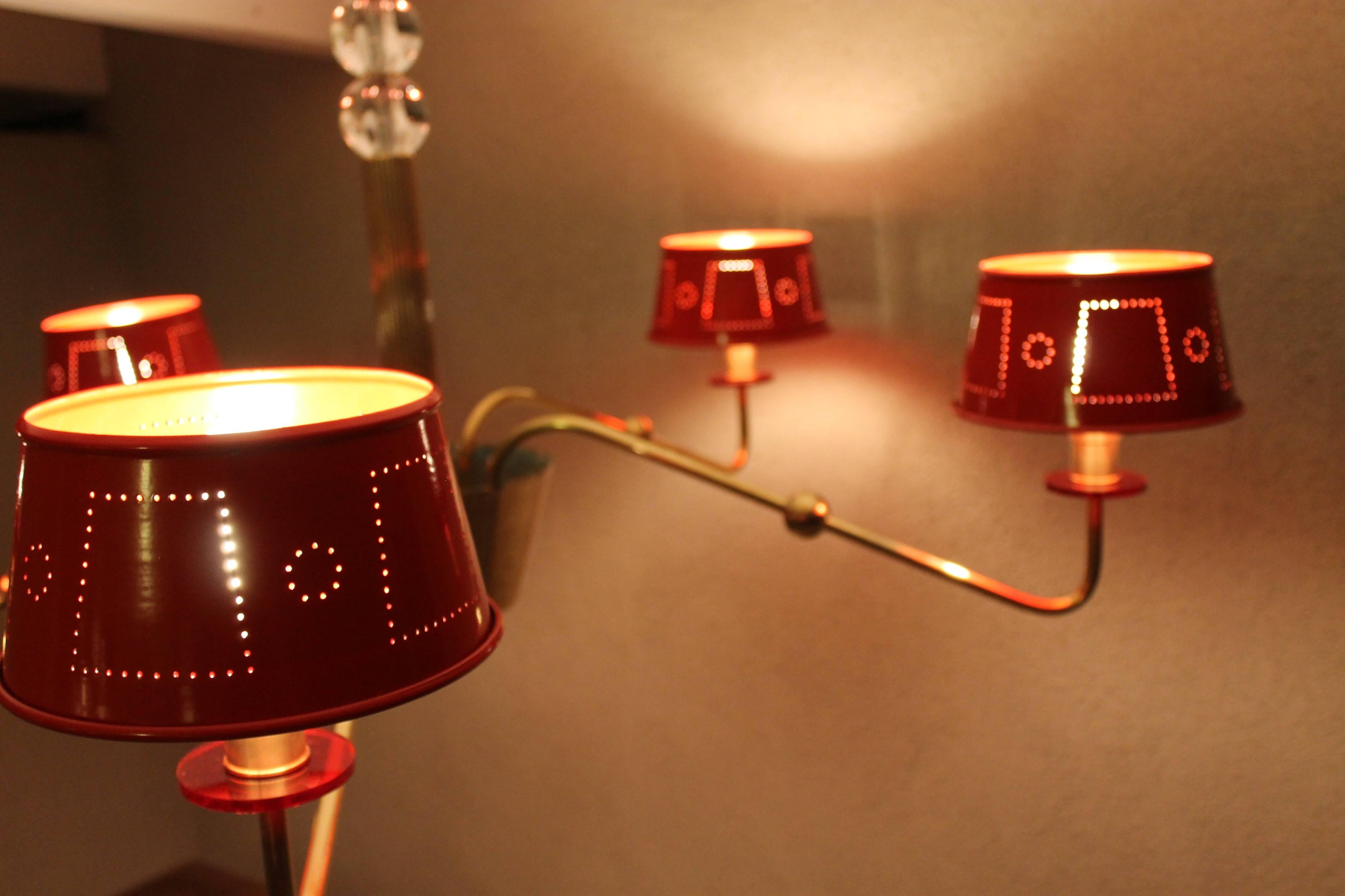 Chandelier in the manner of Tommi Parzinger. The red shades are steel which we had powder coated. All of the brass has been polished back to its original luster. Pair of glass orbs are also original. Each shade has a red Lucite disk. All original