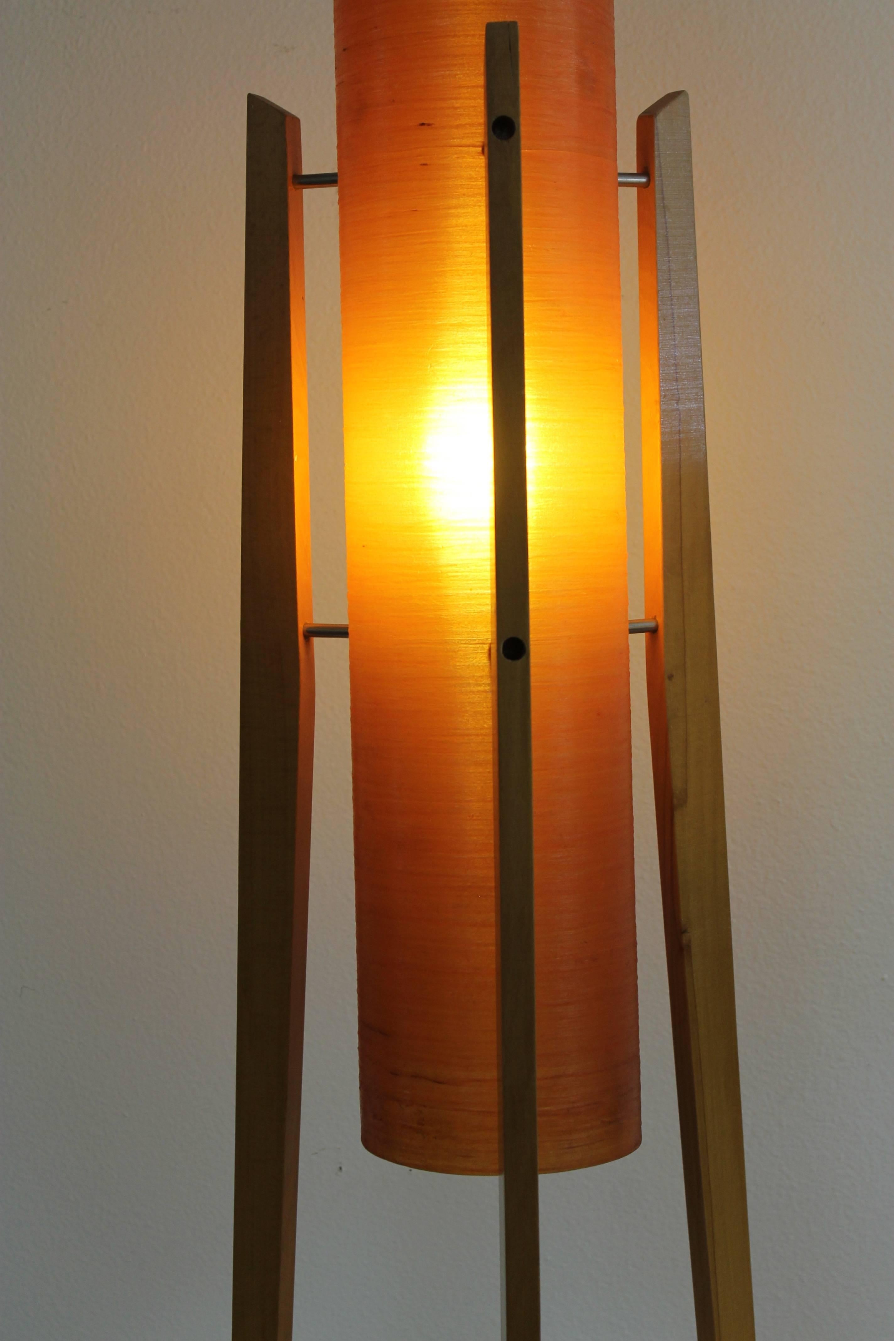 Found in Czechoslovakia, this lamp features a cast resin cylinder in muted orange supported by three tapered hardwood legs. Beautiful orange glow is similar to that of spun fiberglass lamps of the same period. The lamp measures 46.25