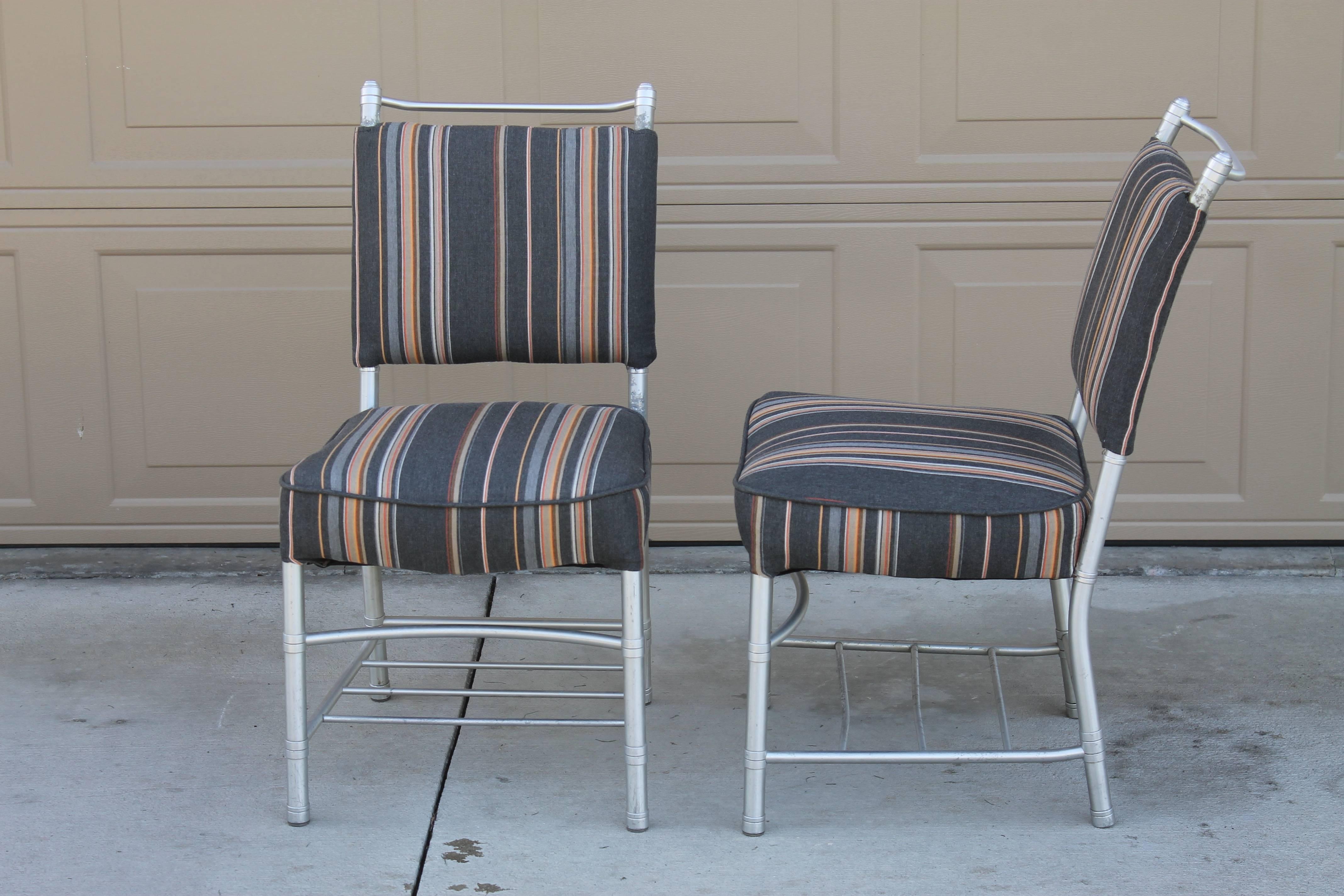 Four Warren McArthur dining chairs. The aluminium shows wear and one of the chairs is missing its cross bar (picture attached). They have been newly reupholstered. They measure 17.5