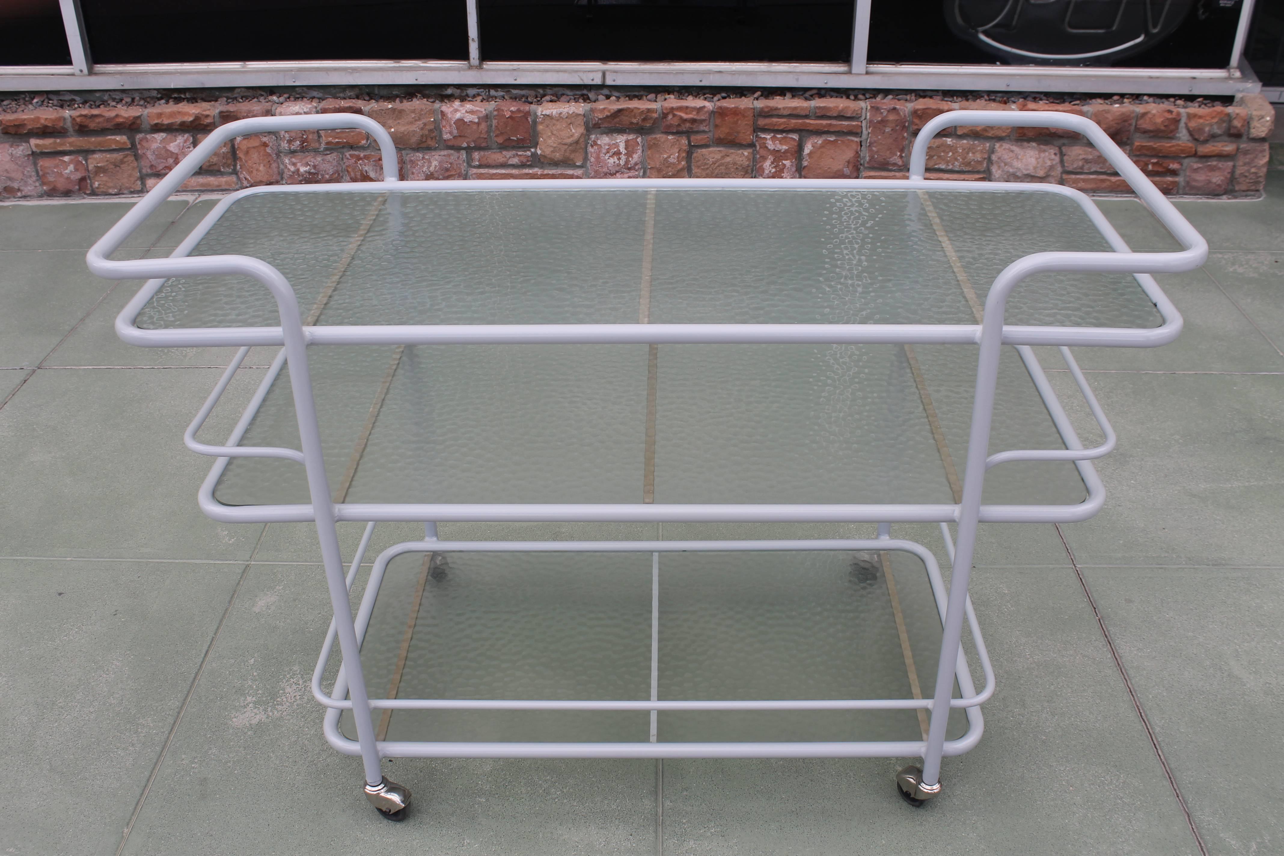 Three tier aluminum bar cart in the style of Walter Lamb. I was recently informed that Richard Frinier designed this cart for Brown Jordan. Contains original glass and steel rollers. This bar cart has been sand blasted and is in its raw state.