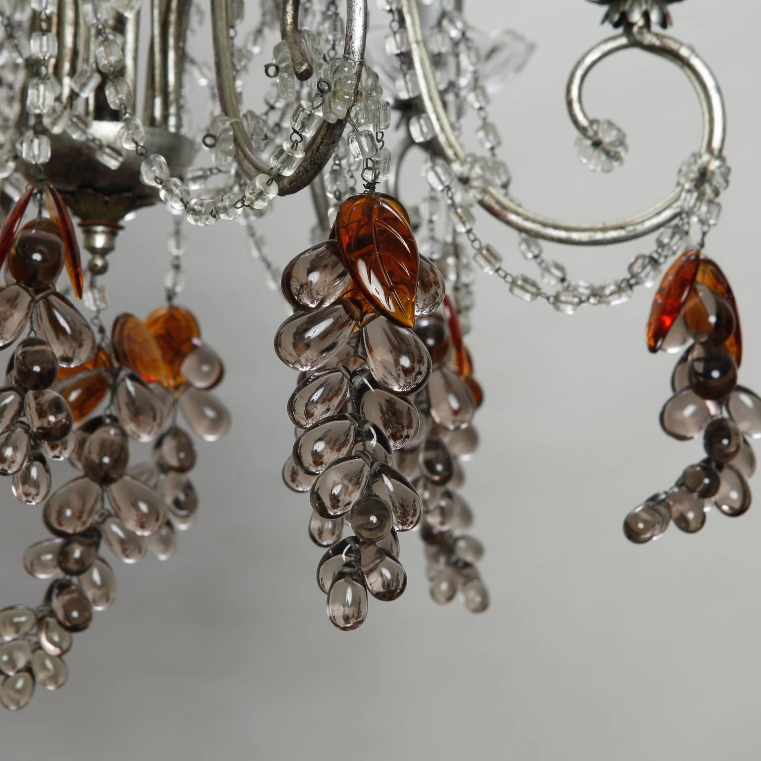 Lampadario con struttura in metallo argentato, perline in cristallo trasparente e diversi grappoli d'uva in vetro fatti a mano con frutti di ametista chiara e foglie in vetro ambrato. Ci sono sei luci a candela con prese a candelabro. Nuovo