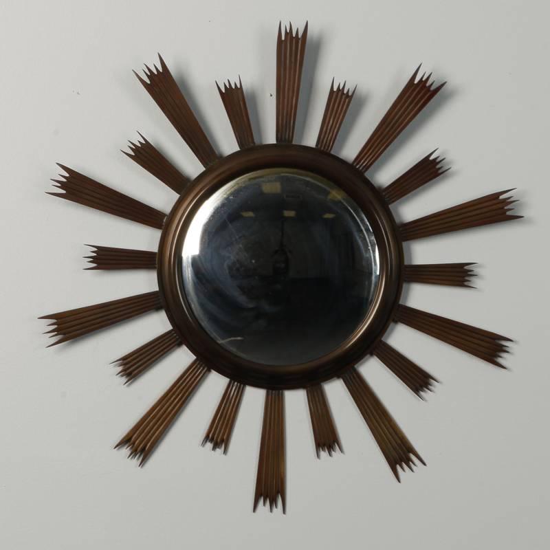 Midcentury sunburst mirror has a dark metal finish frame with alternating long and short rays and a round, convex mirror.