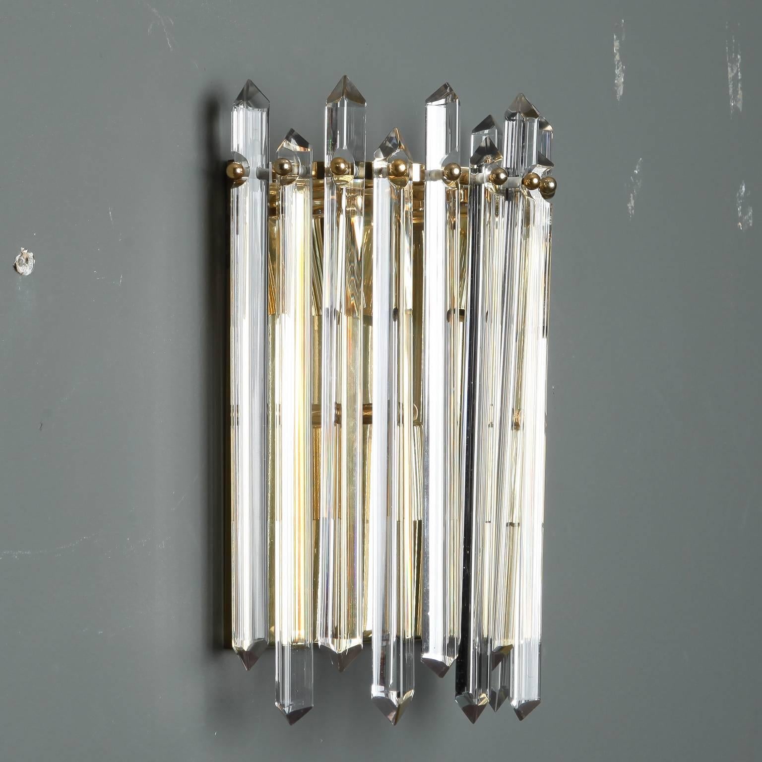 Pair of sconces with polished brass demilune shape base and cut crystal spears suspended at alternating lengths, circa 1970s. New wiring for US electrical standards. Sold and priced as a pair. Multiple pairs available.
