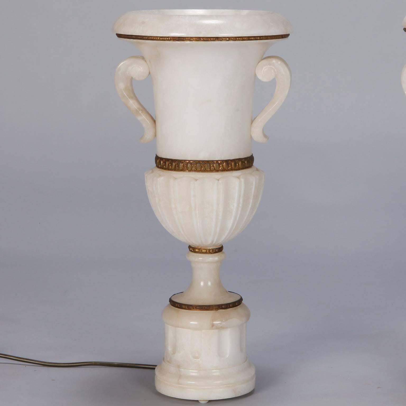 Found in Italy, this pair of, circa 1930s alabaster lamps stand just under 20” tall and feature a Classic urn form with pedestal base, side handles, rounded flared lip and decorative bronze fittings. New wiring for US electrical standards. Sold and