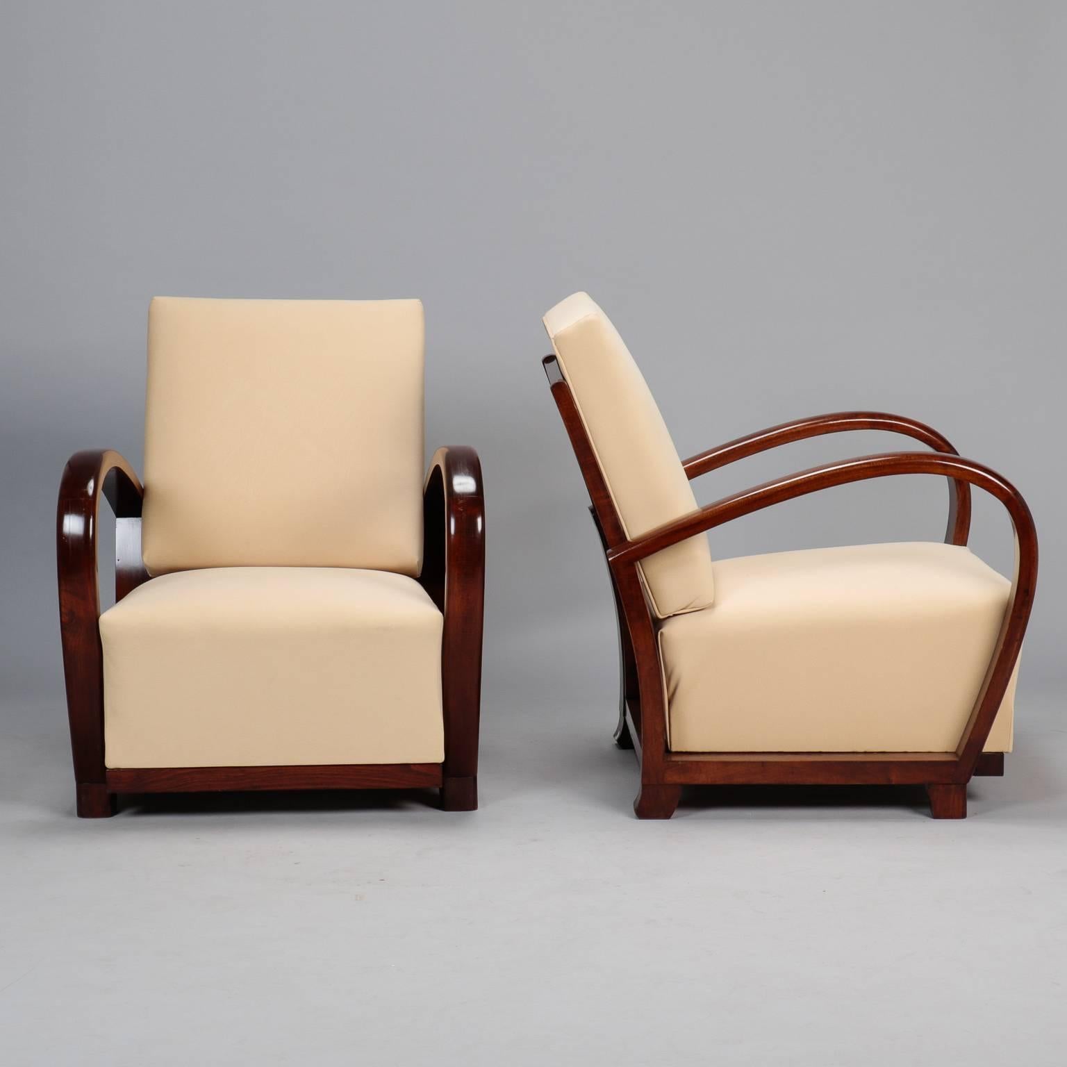 Armchairs with polished palisander frame, slatted backrest and prominent curvy arms, circa 1930s. New bone colored micro suede upholstery. Measures: Arms are 24.5” high, seats are 14.5” high and 21” deep. Sold and priced as a