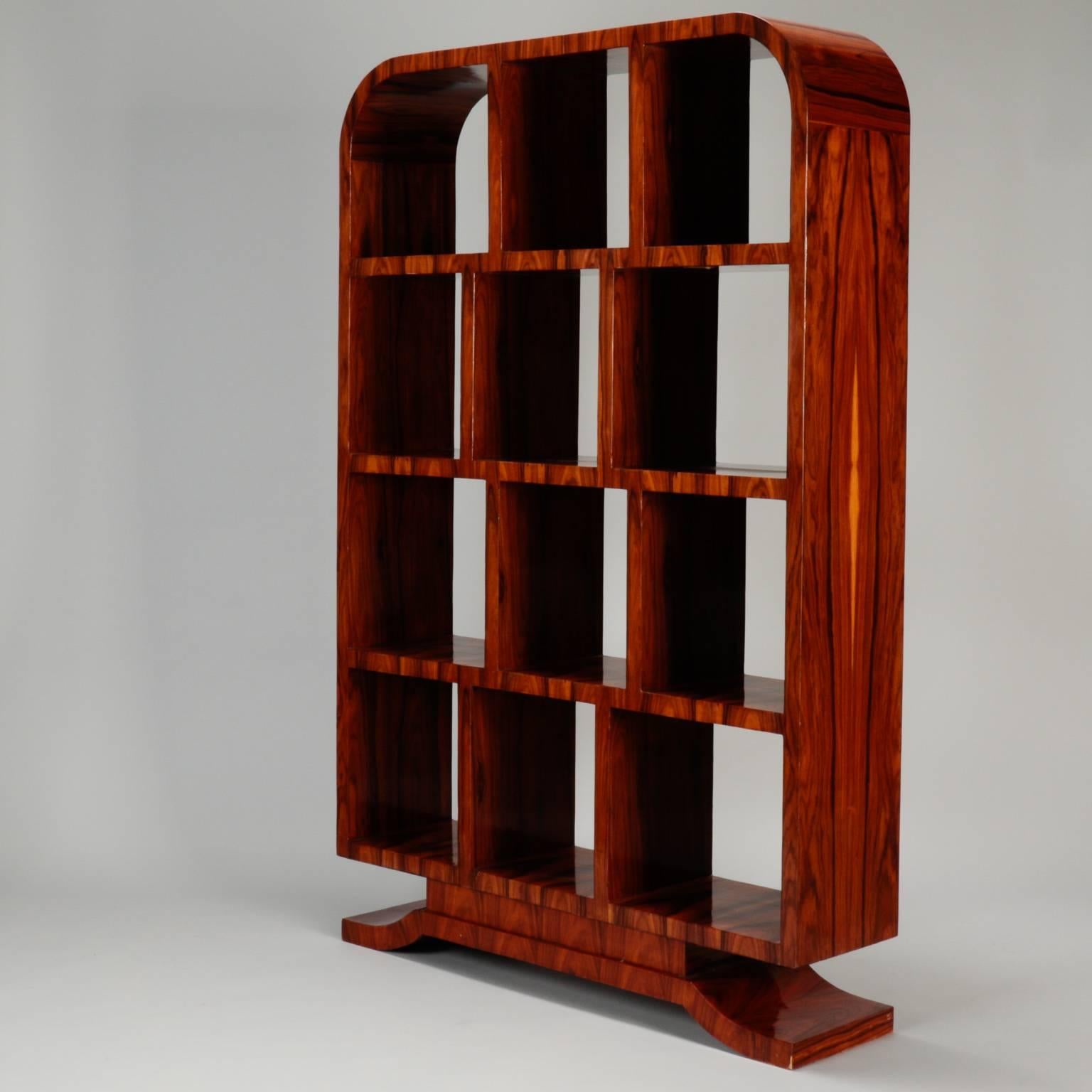 Art Deco era étagère of polished burl wood with footed pedestal base and four shelves with fixed dividers and an elegant, arched top, circa 1930s.
   