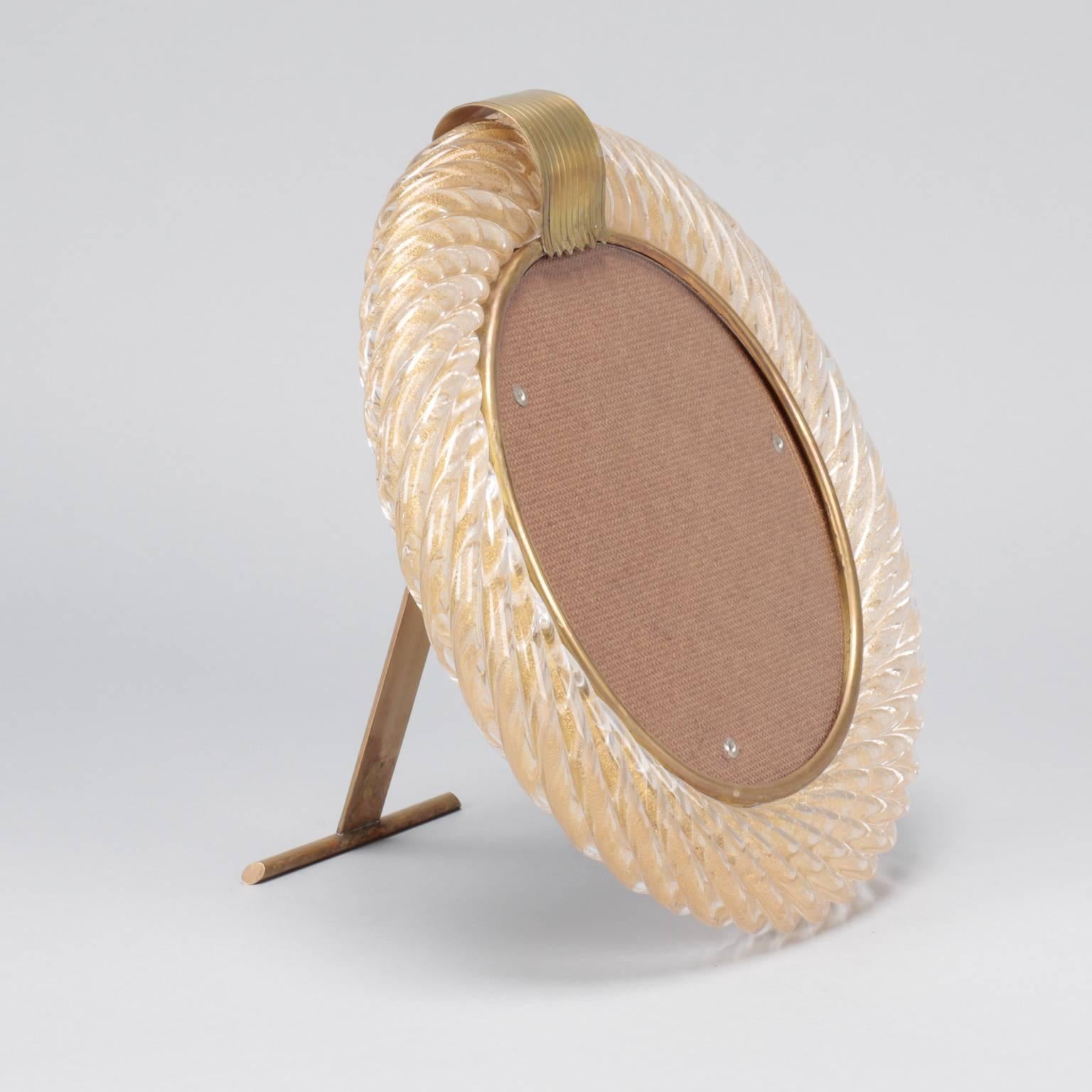 Signed Barovier & Toso round glass picture frame in a pale peach pink ribbed glass with gold inclusions and brass hardware. Manufacturer name is incised on back stand, circa 1940.