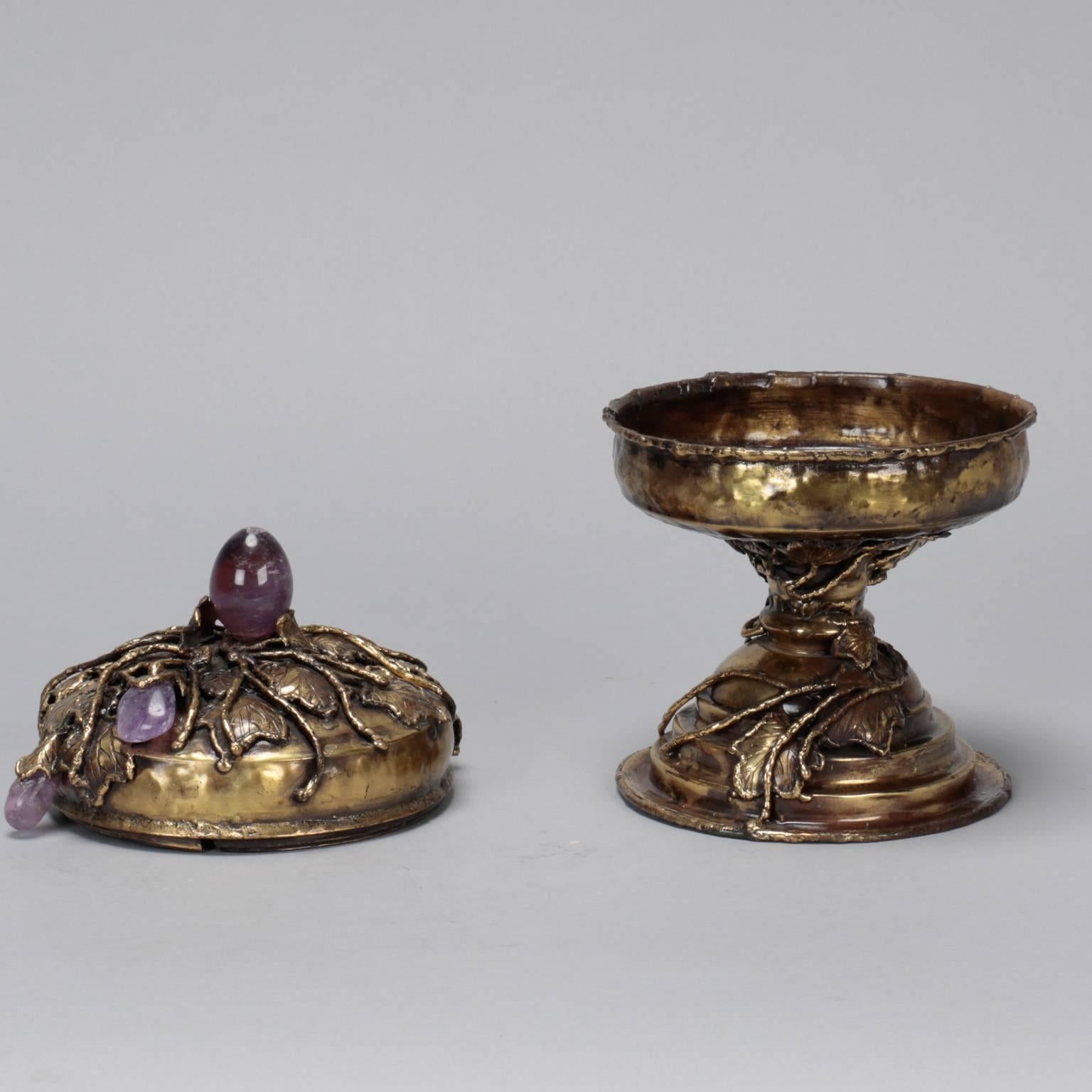 Signed Lionel on inside of footed base, this bronze colored hand worked lidded tazza is decorated with a leaf and vine motif and amethyst stones. Other pieces by this artist available at the time of this posting. Please inquire.
  