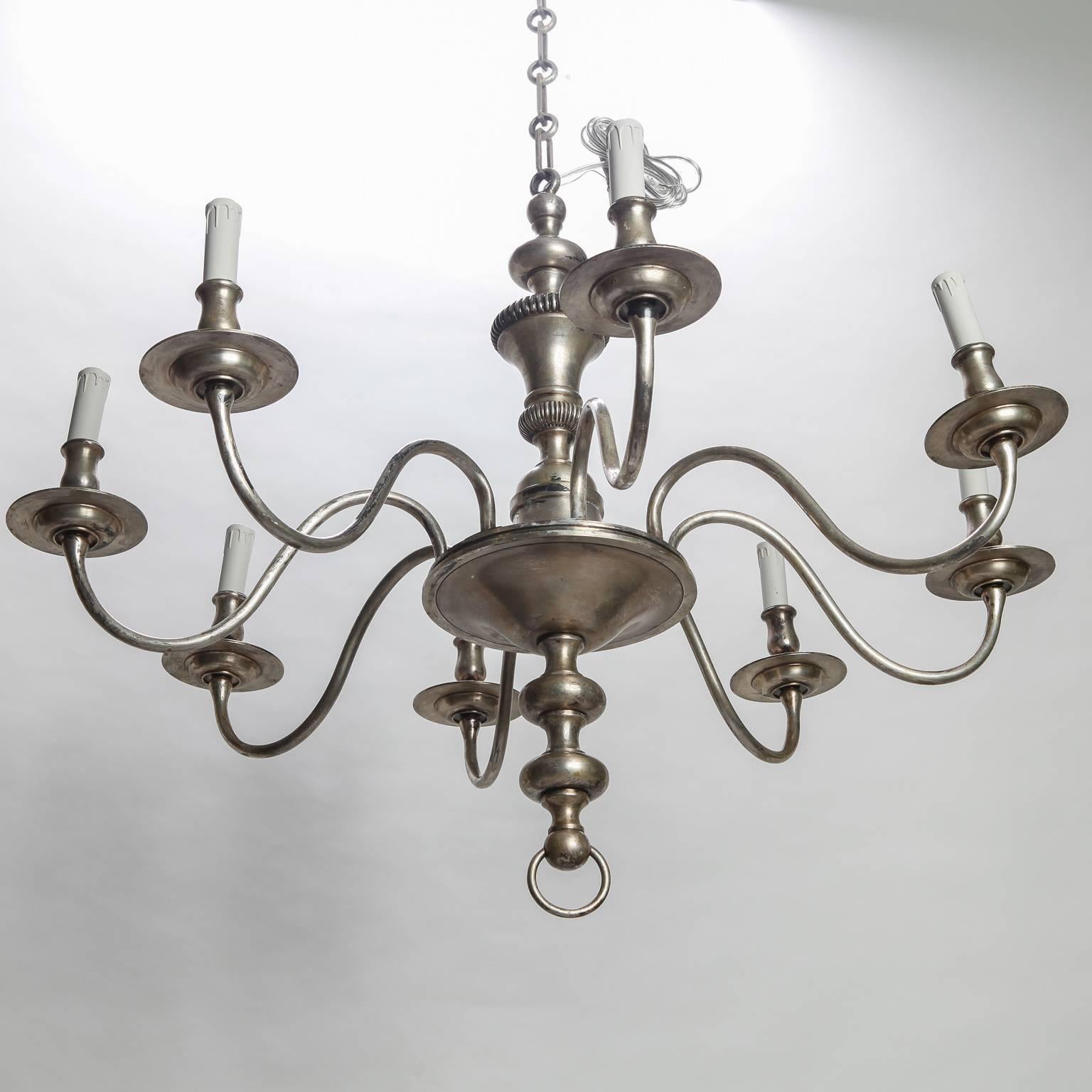 French eight-light silver finish metal chandelier dates from 1940s. Center shaft has ridged details and supports eight slender, curved arms with candle style lights. New wiring for US electrical standards.
 