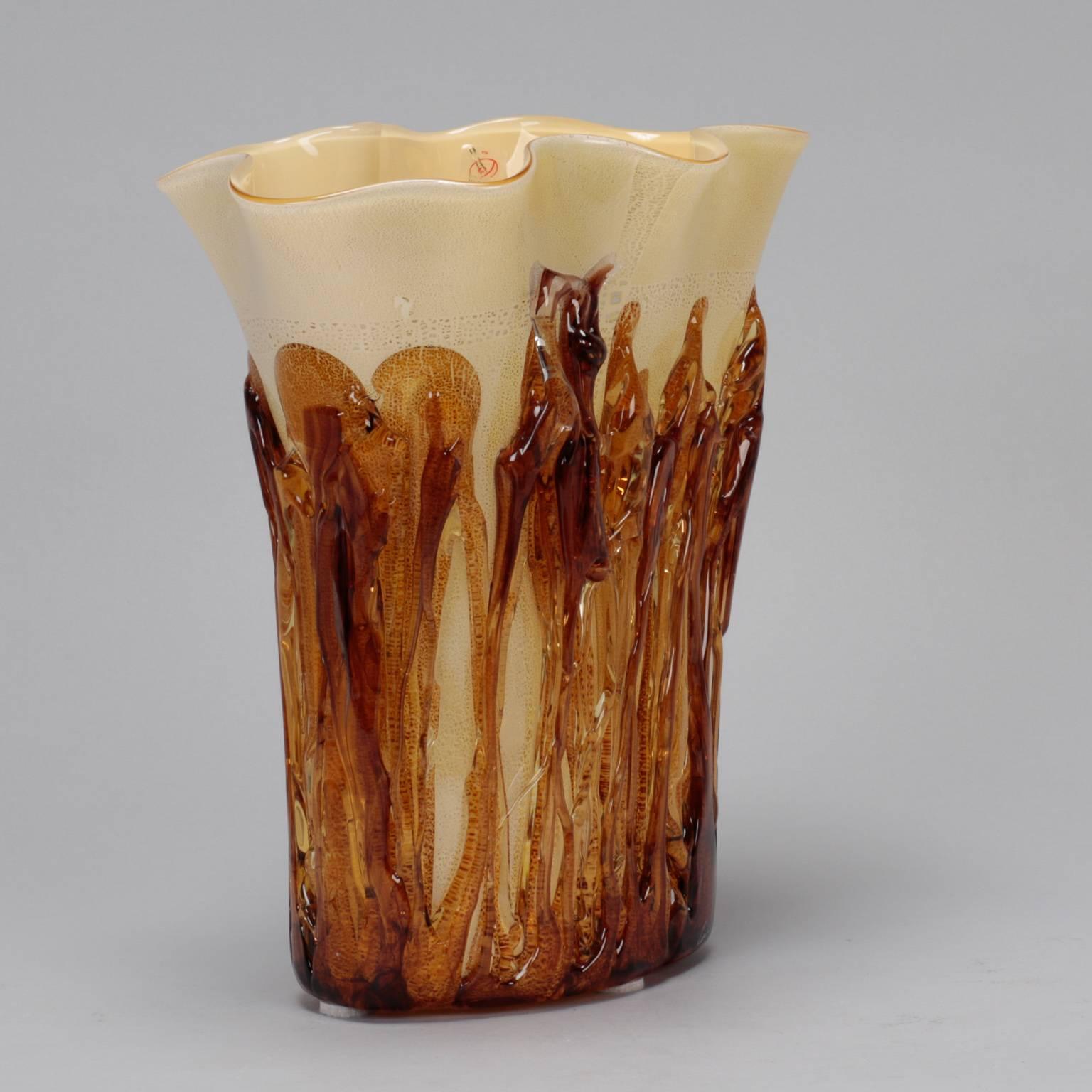 Tall cream color Murano vase encased in applied gold glass. 

Cream colored vase is just over 12” tall with a flared and slightly ruffled rim, circa 1990s. Amber colored glass strings encase the bottom and sides for textural and colorful accent.