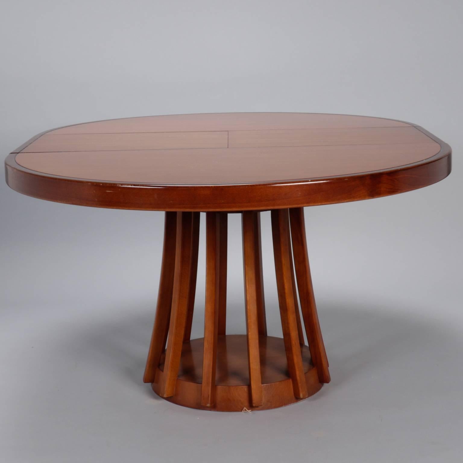 Round walnut dining table with contrasting darker band, slatted center support and round pedestal base, circa 1960s. Self storing butterfly leaf adds 16”. Found in Italy, no manufacturer’s marks found. Some minor scuffs to surface finish.
   