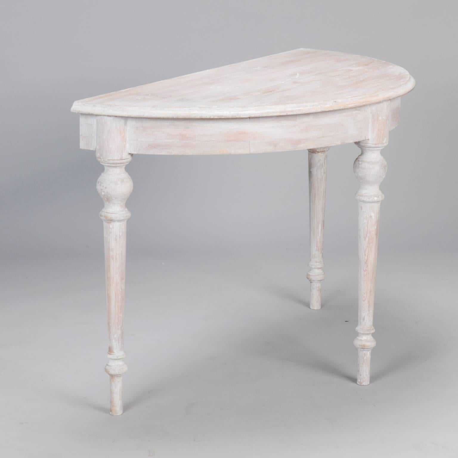 Pair of French demilune tables with turned legs and white painted finish, circa 1930s. These versatile pieces can be used as a pair of demilune tables, joined together to form a single round table or use the 17.5” leaf for a larger, oval table.