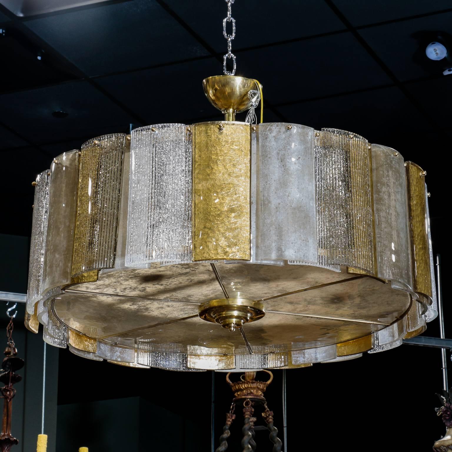 Mid-Century round hanging Murano glass lighting fixture dates from the 1970s. Drum shaped fixture is 36” diameter and consists of clear and gold colored panels of Murano glass with brass tone metal frame and ceiling canopy. New electrical wiring for