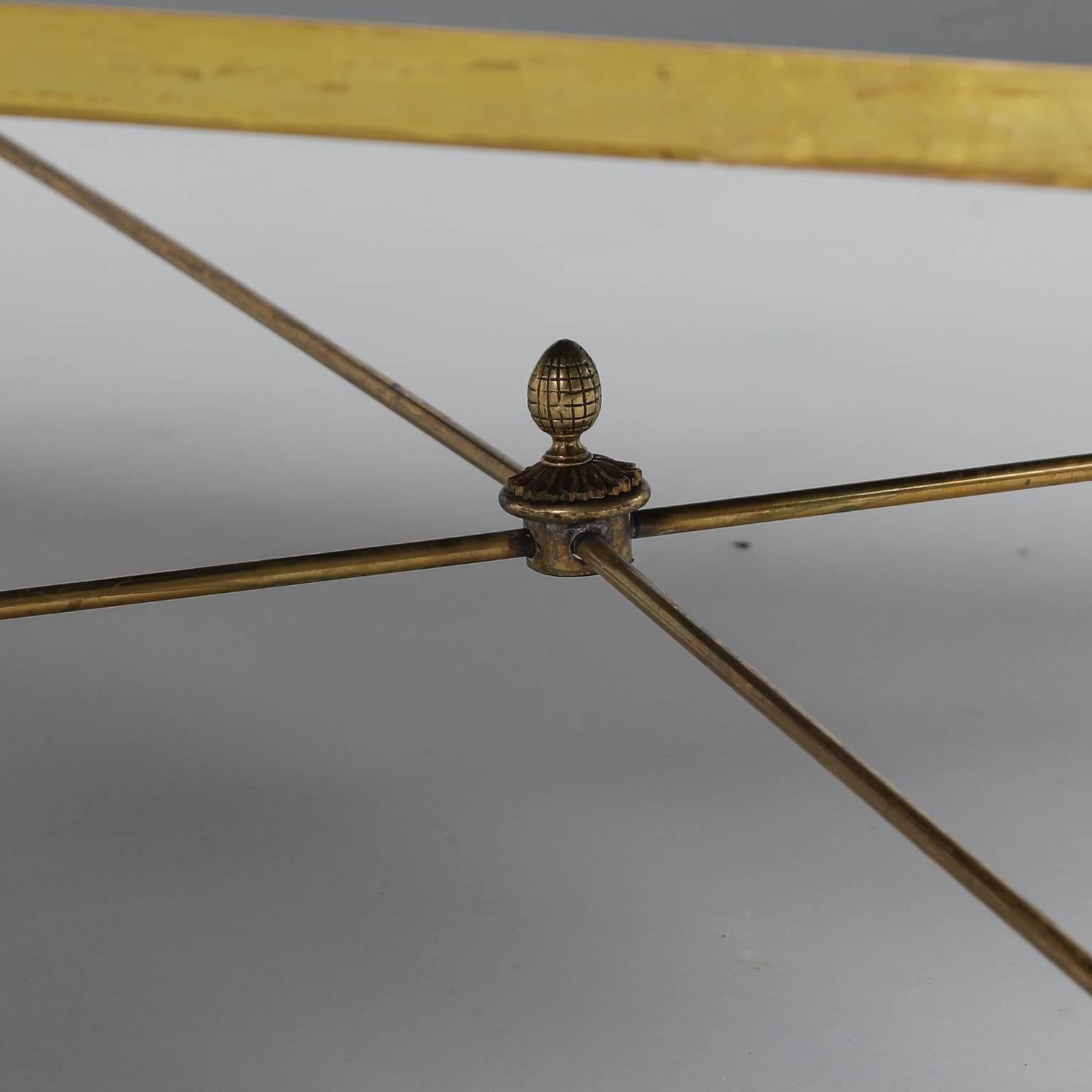 French glass and brass cocktail or coffee table has a brass frame with a finial topped X-form stretcher and detailed swan figures at the top of each corner and webbed swan feet support the table’s black glass top. Excellent vintage condition with