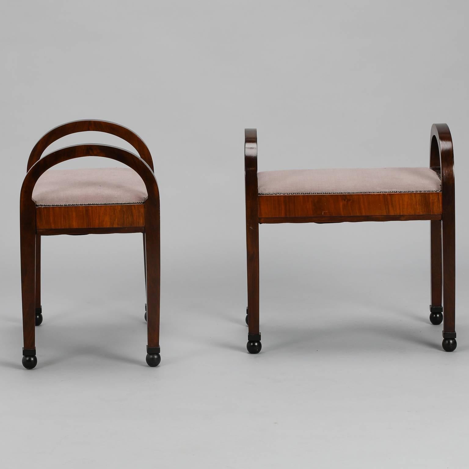 Pair of French Art Deco era polished wood benches with tall, arched sides and upholstered seats, circa 1930s. Newly upholstered seats have brass nailhead trim, ball feet and contrasting figured wood stretchers. Sold and priced as a pair.

  