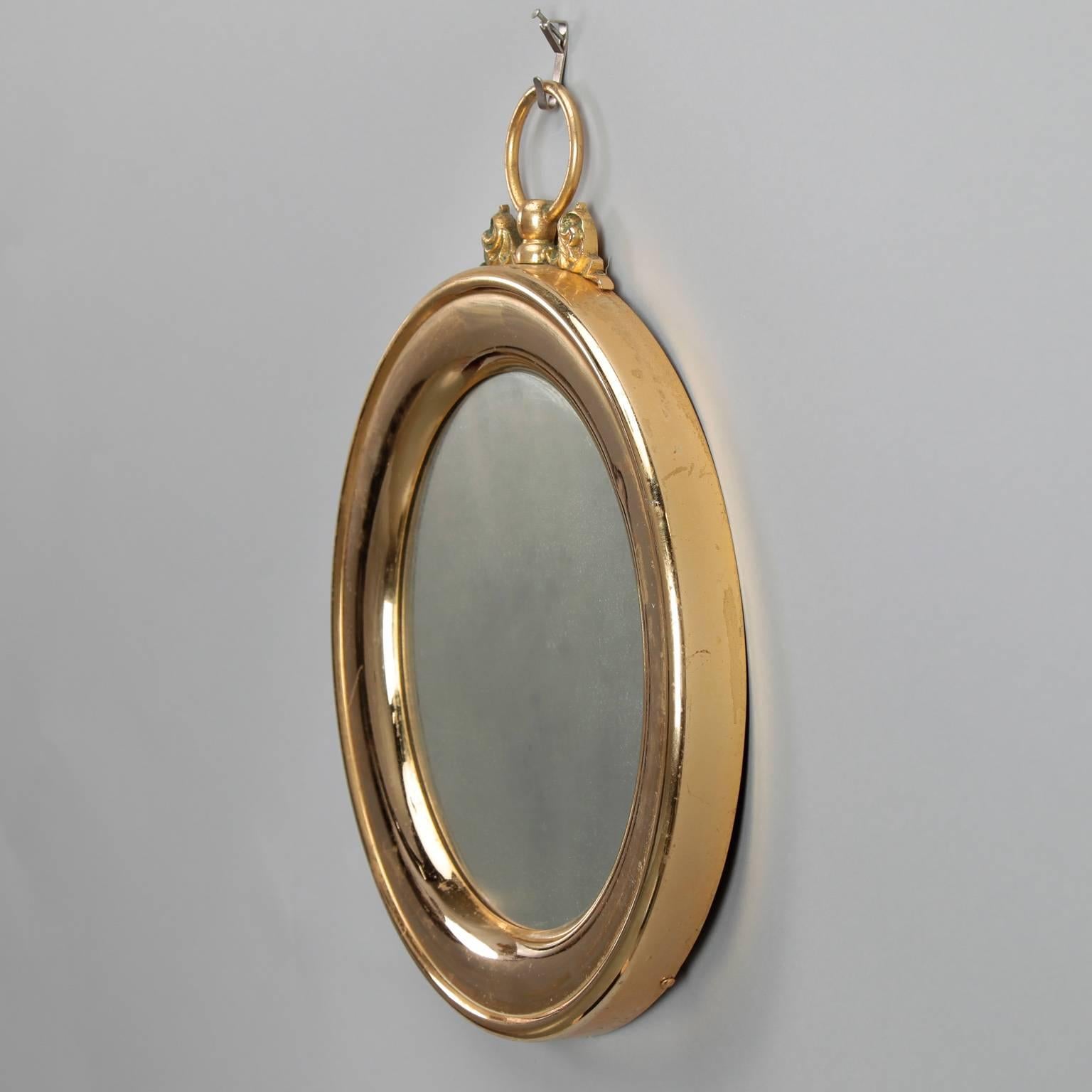 Polished brass framed round wall mirror has the whimsical shape of a stop watch, circa 1950s. Mirror is 9” diameter.