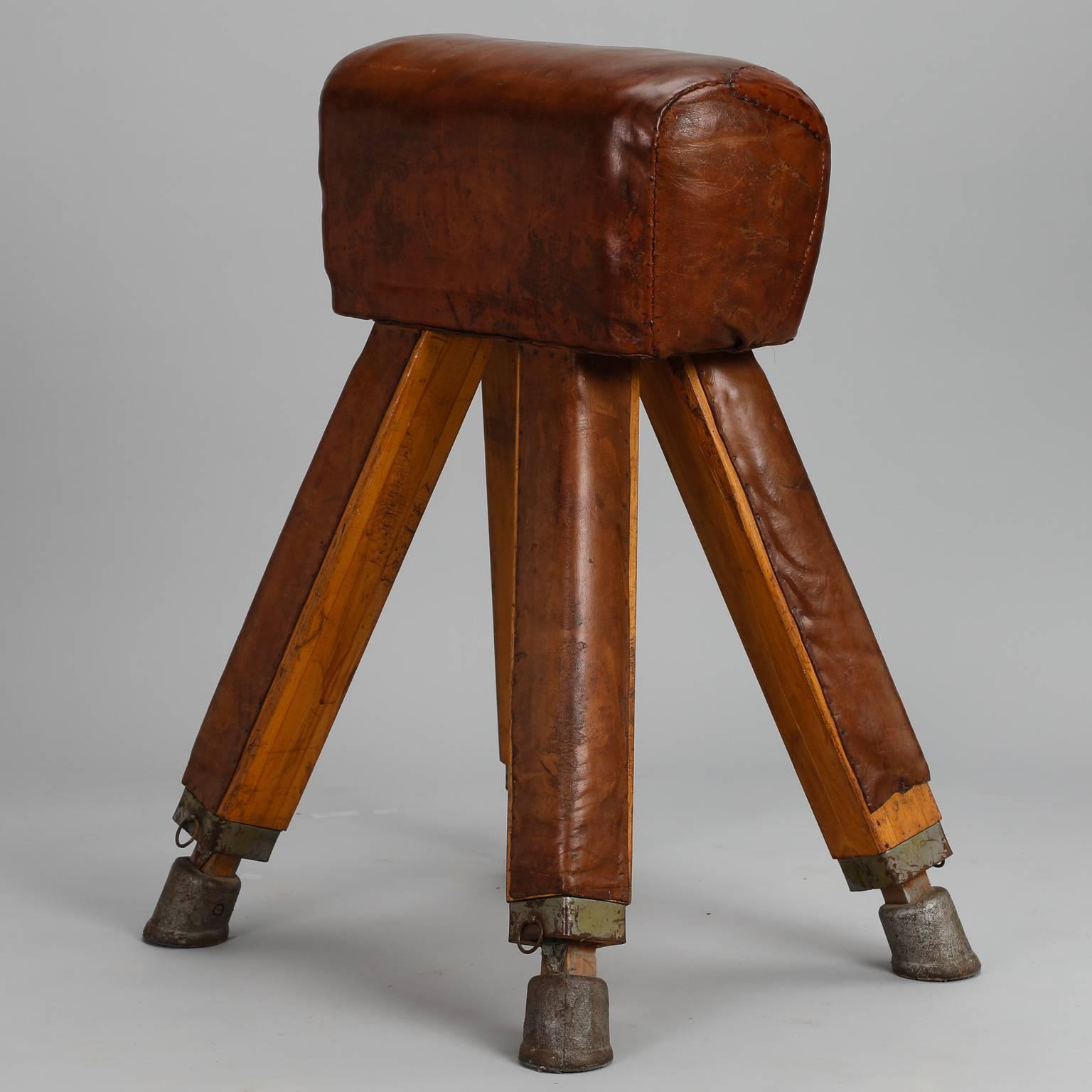 Gym vaulting horse has metal feet, a beechwood frame and leather upholstery, circa 1910, French. Leather was repaired with hand-stitched patch. This is a heavy, substantial piece of equipment with a lot of visual impact.