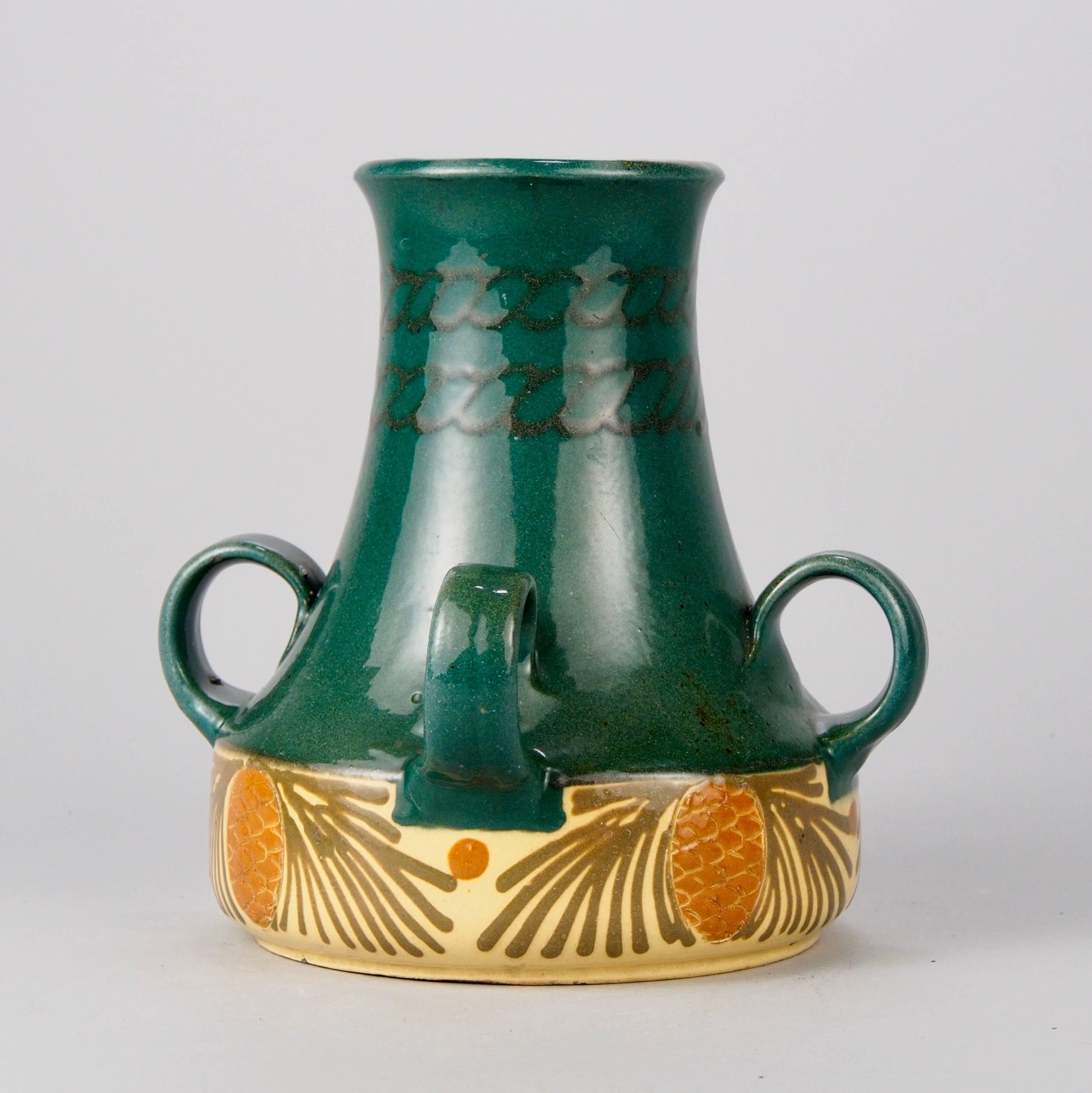 Dating from approximately 1925, this superb Art Nouveau / Jugendstil art pottery vase is signed and made by famed Elchinger et Fils, a family owned Alsatian ceramic studio founded in 1834. This piece is hand made with four handles, a deep green