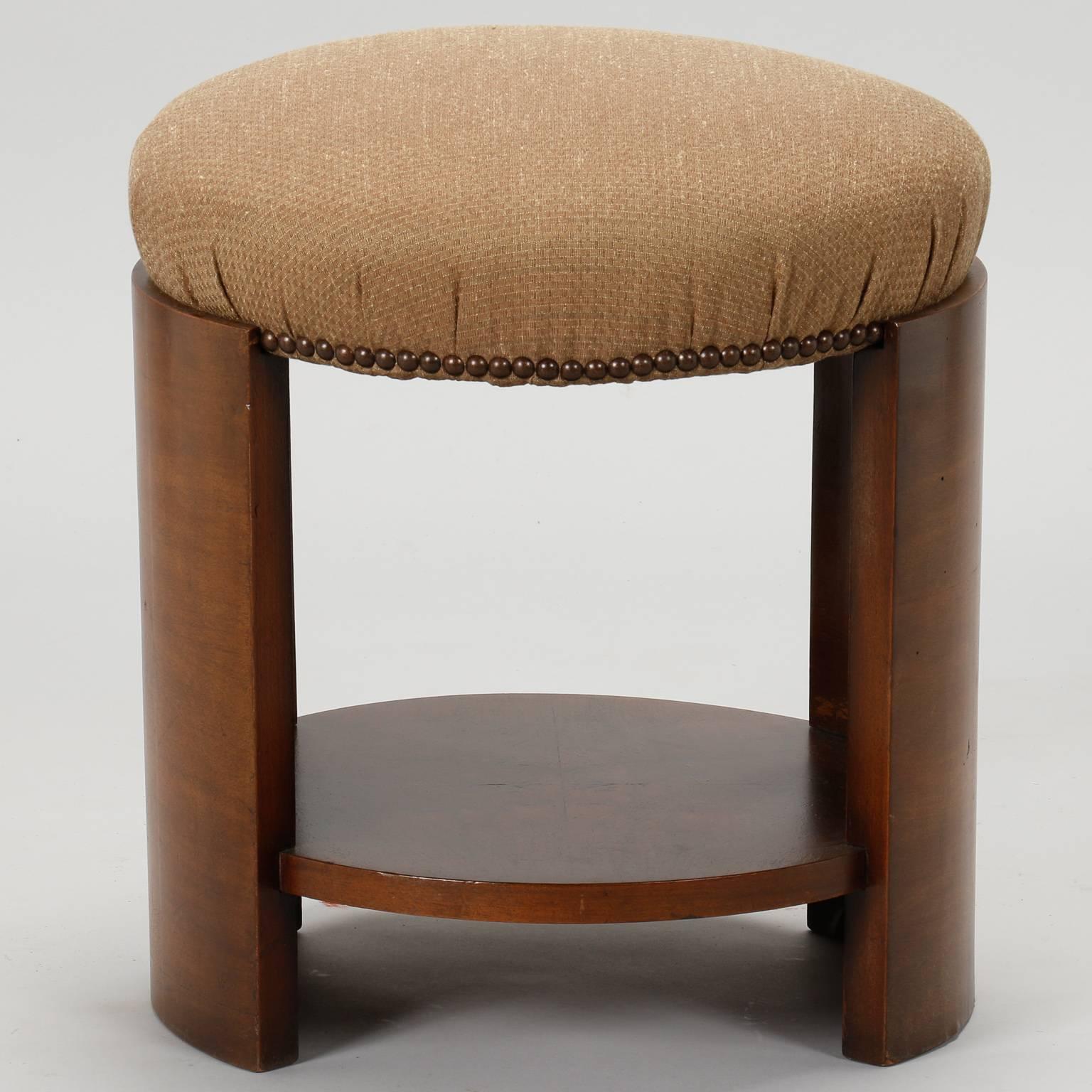 French Art Deco stool, circa 1930s. Round upholstered seat has been newly covered and trimmed with brass nailheads, curved walnut legs and round lower support. Size: Seat is 19” high.