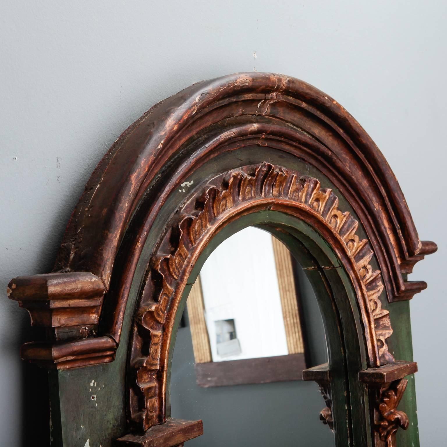 French arched mirror has an elaborate green painted and carved frame with extensive gilded detail, circa 1880s.  Actual Mirror Size:  35.5” h x 18” w
 