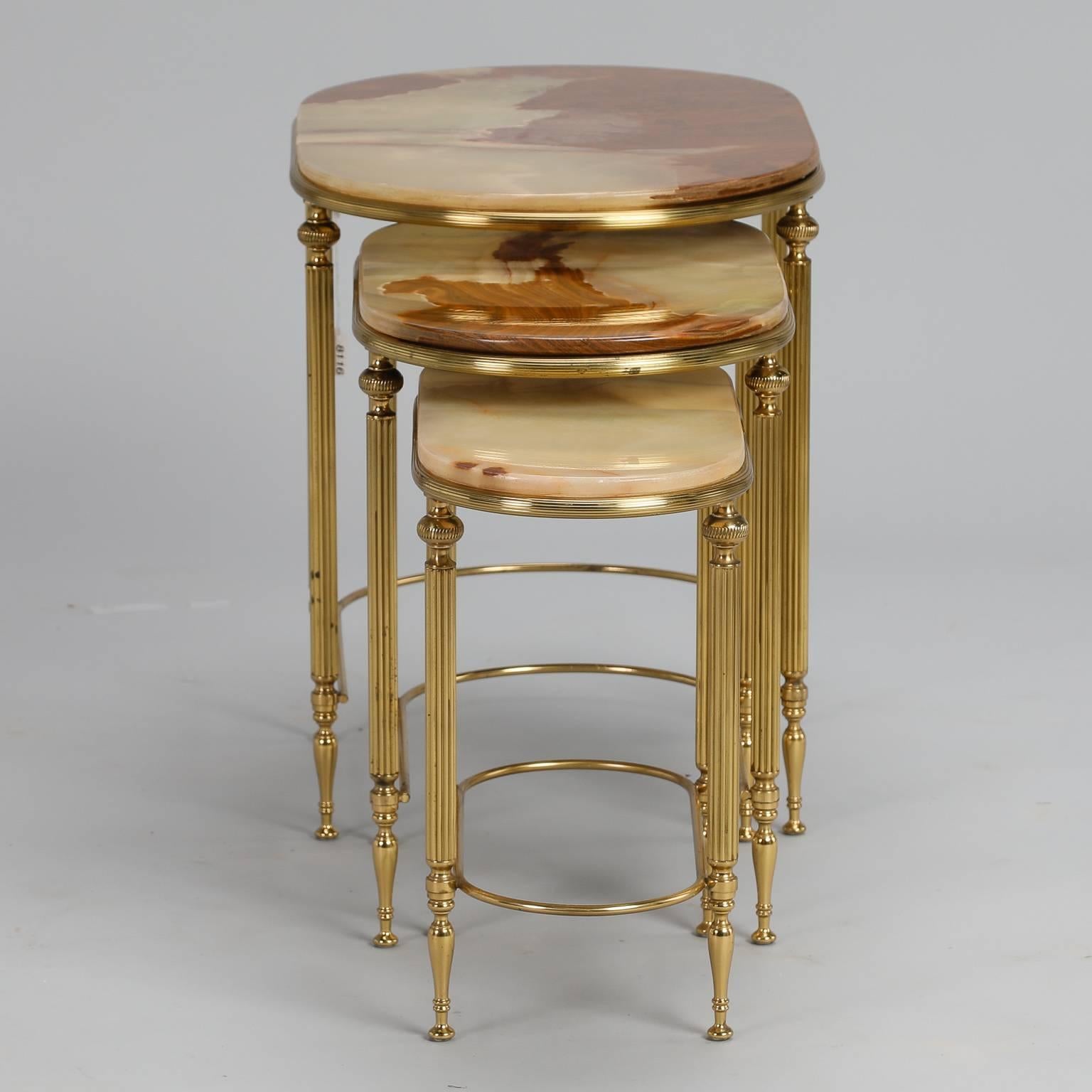 Found in France, circa 1950s trio of oval nesting or stacking tables with brass frames and onyx table tops. Reeded brass legs, beautiful depth and warm amber coloration to onyx. Sold and priced as a set. Dimensions shown are for largest table.
