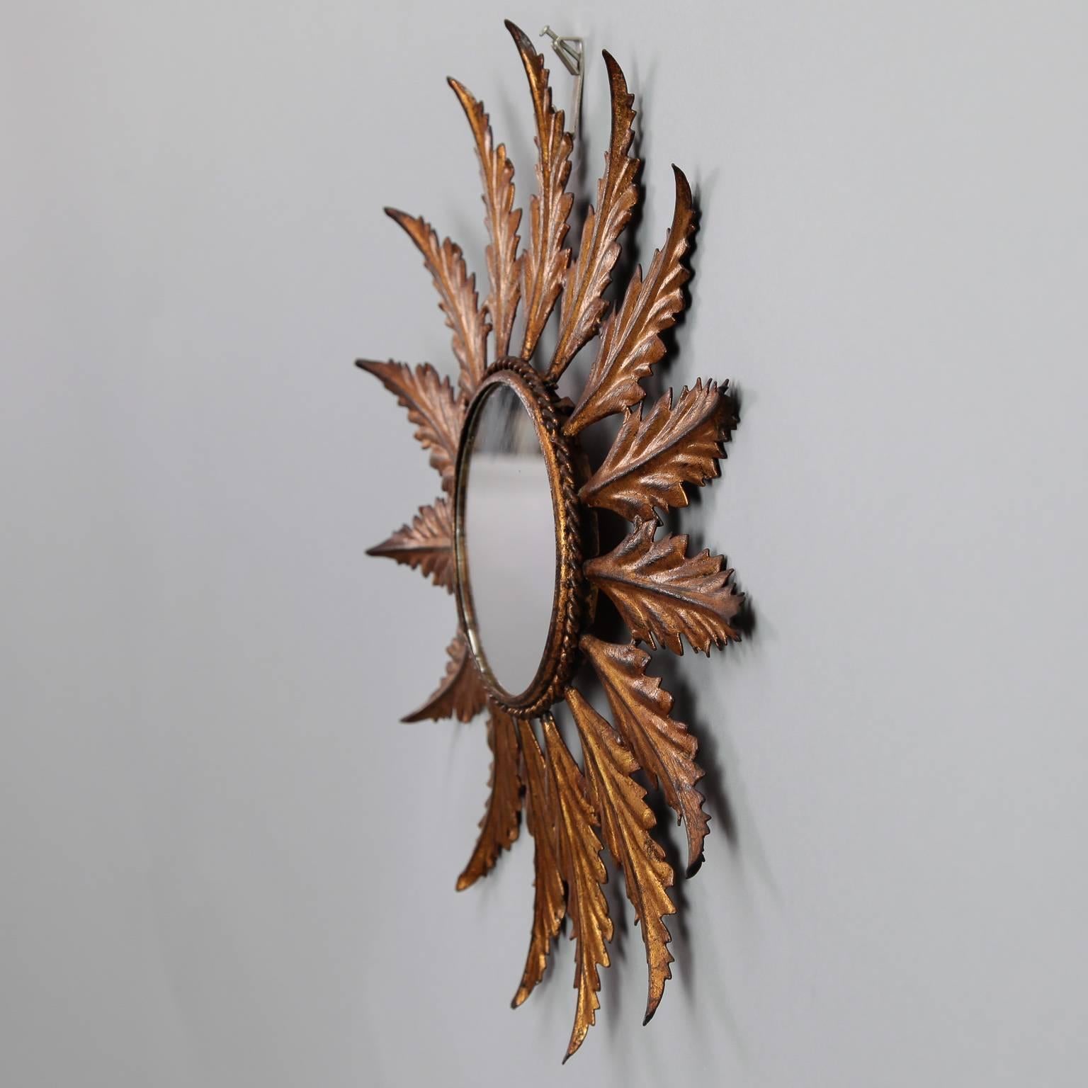 At just over 14” in diameter, this circa 1950s Italian sunburst mirror has a gilt metal frame with leaf-form rays and a twisted inner rim.