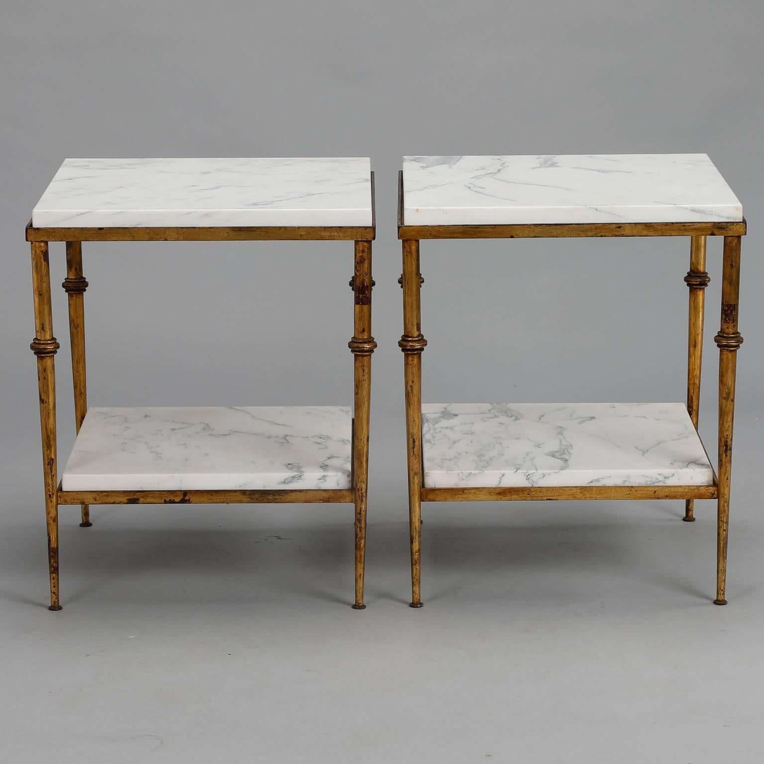 Pair of two-tier Spanish side tables feature tapered gilt metal frames marble table tops in white with gray veining, circa 1970s. Excellent vintage condition. Sold and priced as a pair.