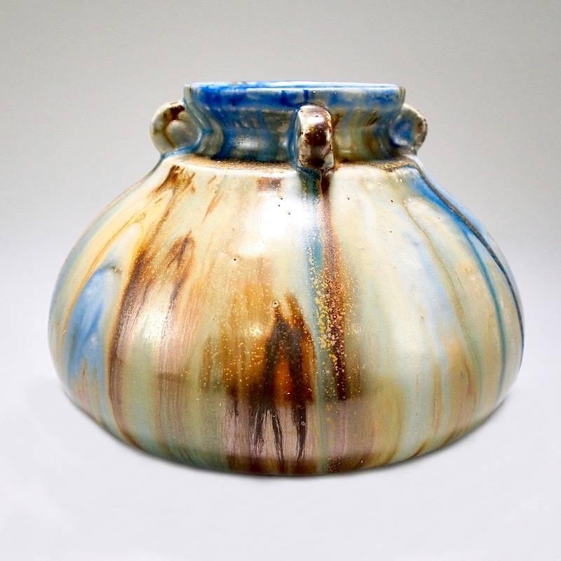 Ceramic vessel designed by Roger Guerin of Belgium, circa 1930s. Globe shaped body with four handles at the neck and a streaky drip glaze in shades of blue and earthy browns. Incised signature on the bottom.