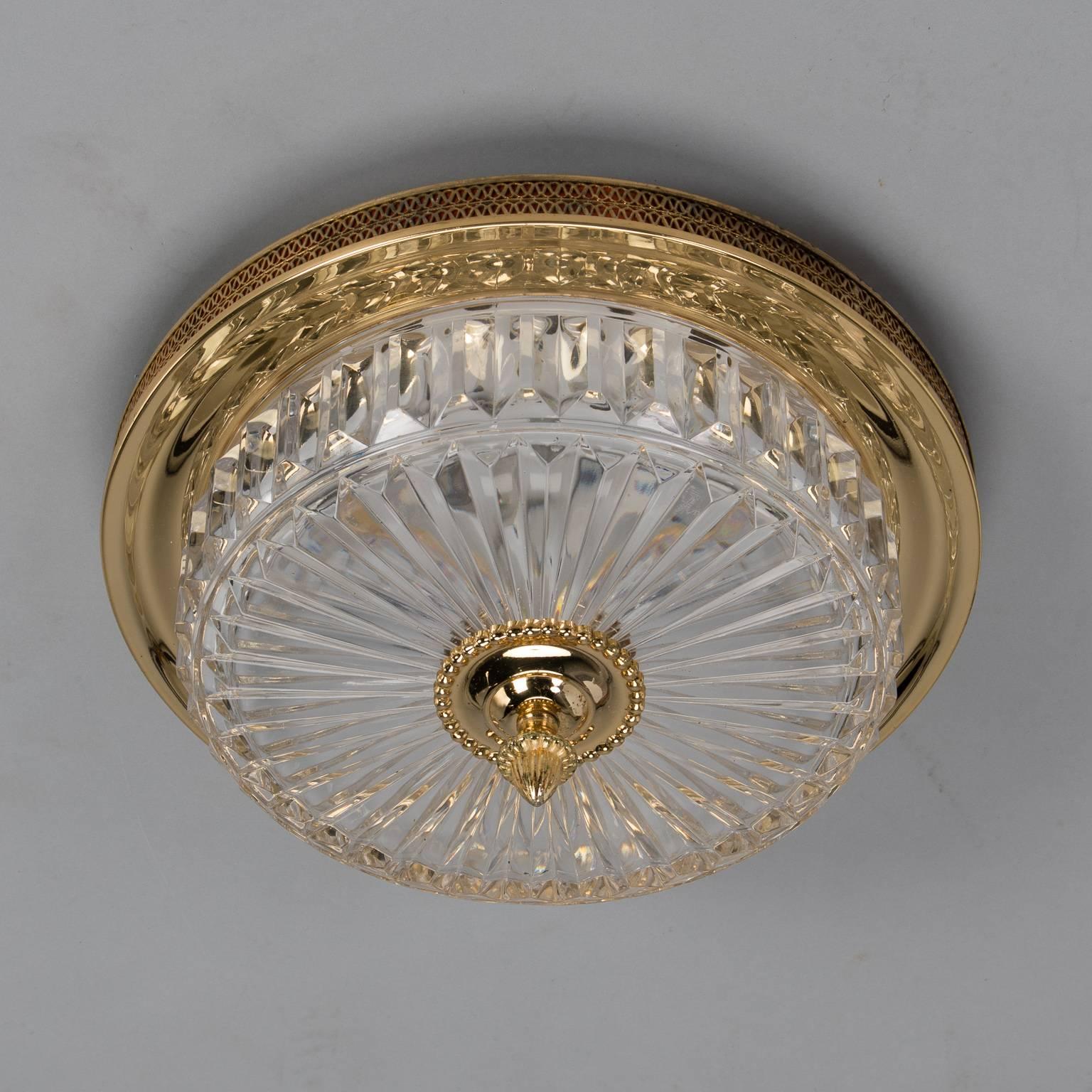 Round flush mount light fixture has a brass frame with open work border and fluted crystal bowl with brass centre, circa 1920s. Two full size internal sockets. Electrical wiring has been updated to US standards.