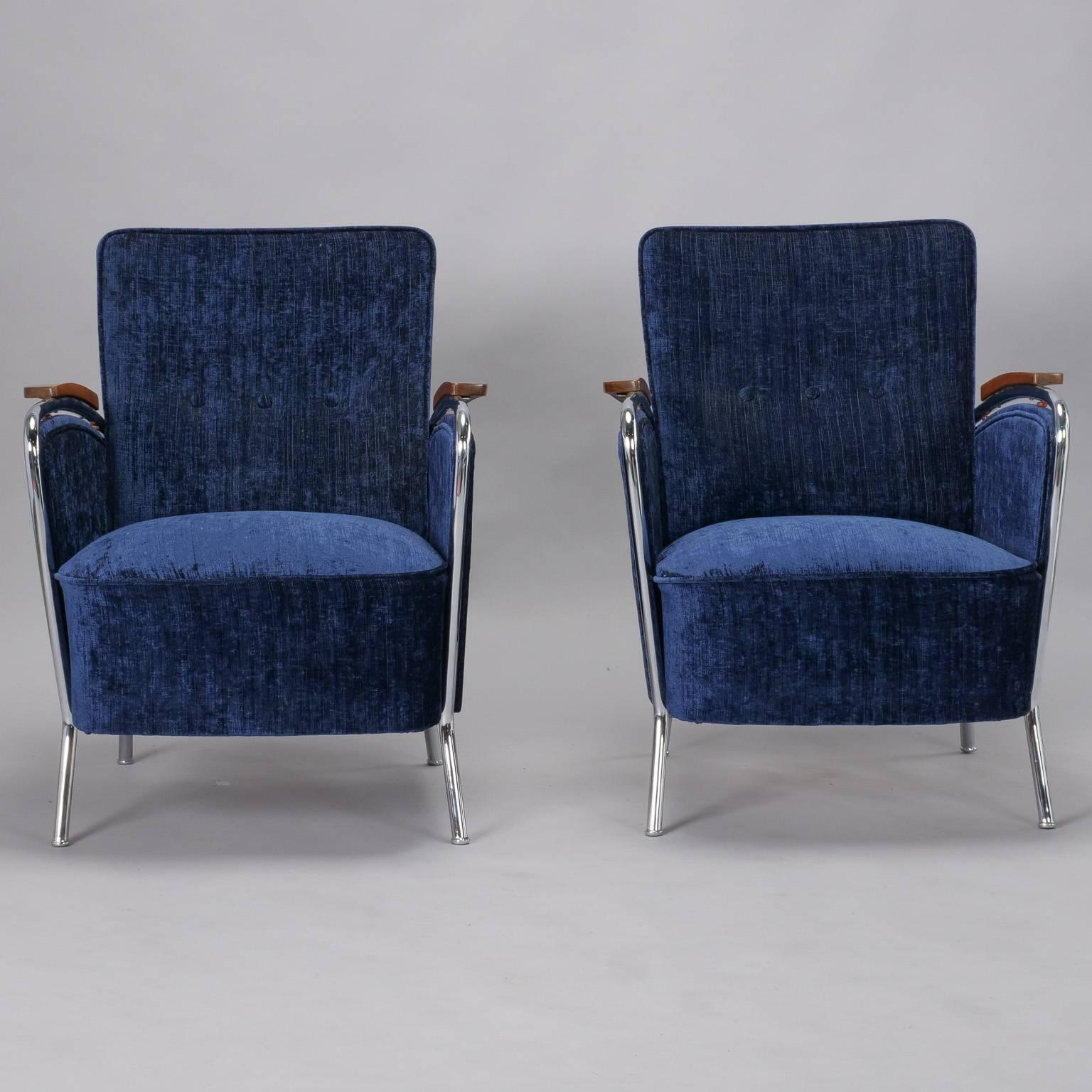 Pair of Bauhaus armchairs have a curvy polished steel frame, wood accented arm rests and have been recently upholstered in blue chenille, circa 1930s. Unknown maker. Measure: Seats are 18.5” high and 20.5” deep. Sold and priced as a pair.