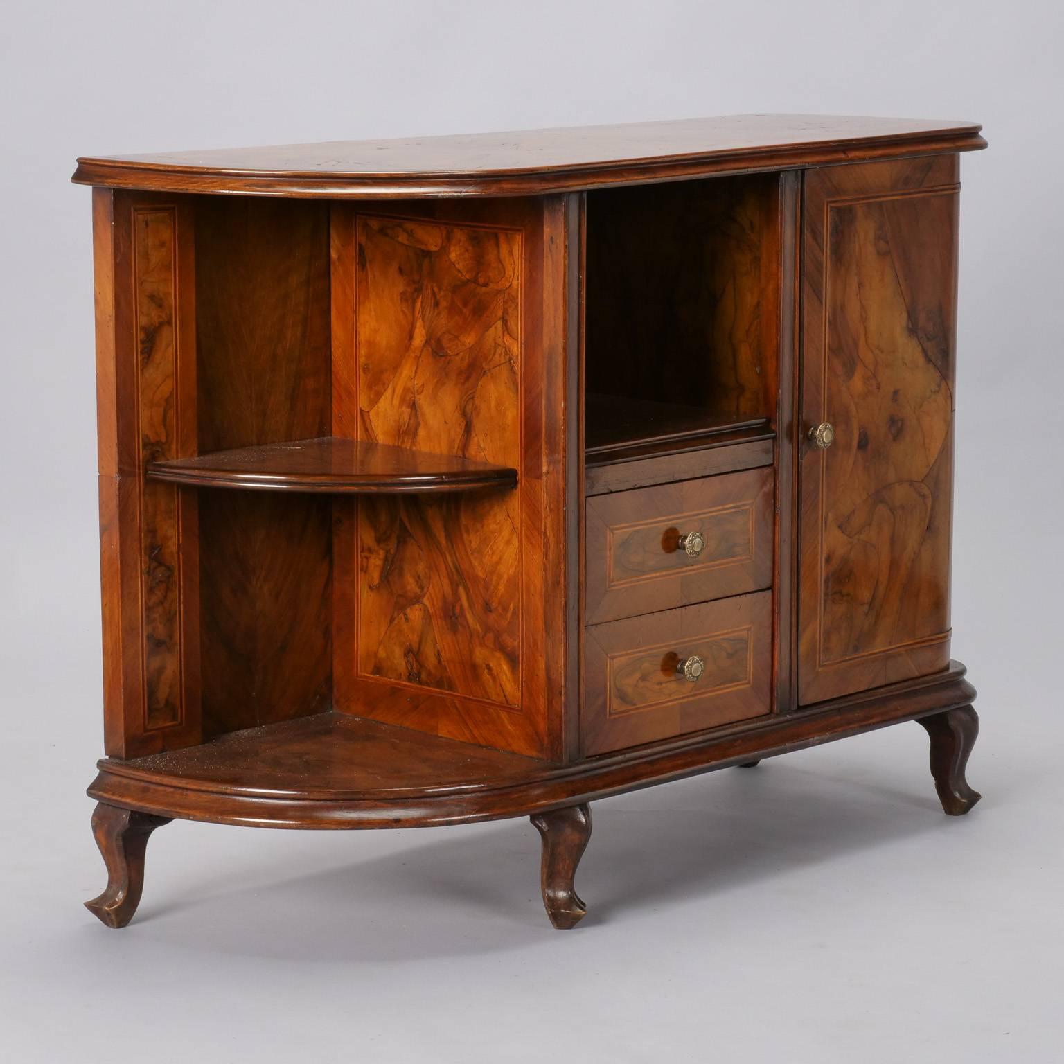 Italian burr walnut side cabinet has curved shape, open storage compartment over two functional drawers in the center flanked by a open corner shelf and cabinet with hinged door and one internal shelf, circa 1930s. Dramatic burr wood veneer and
