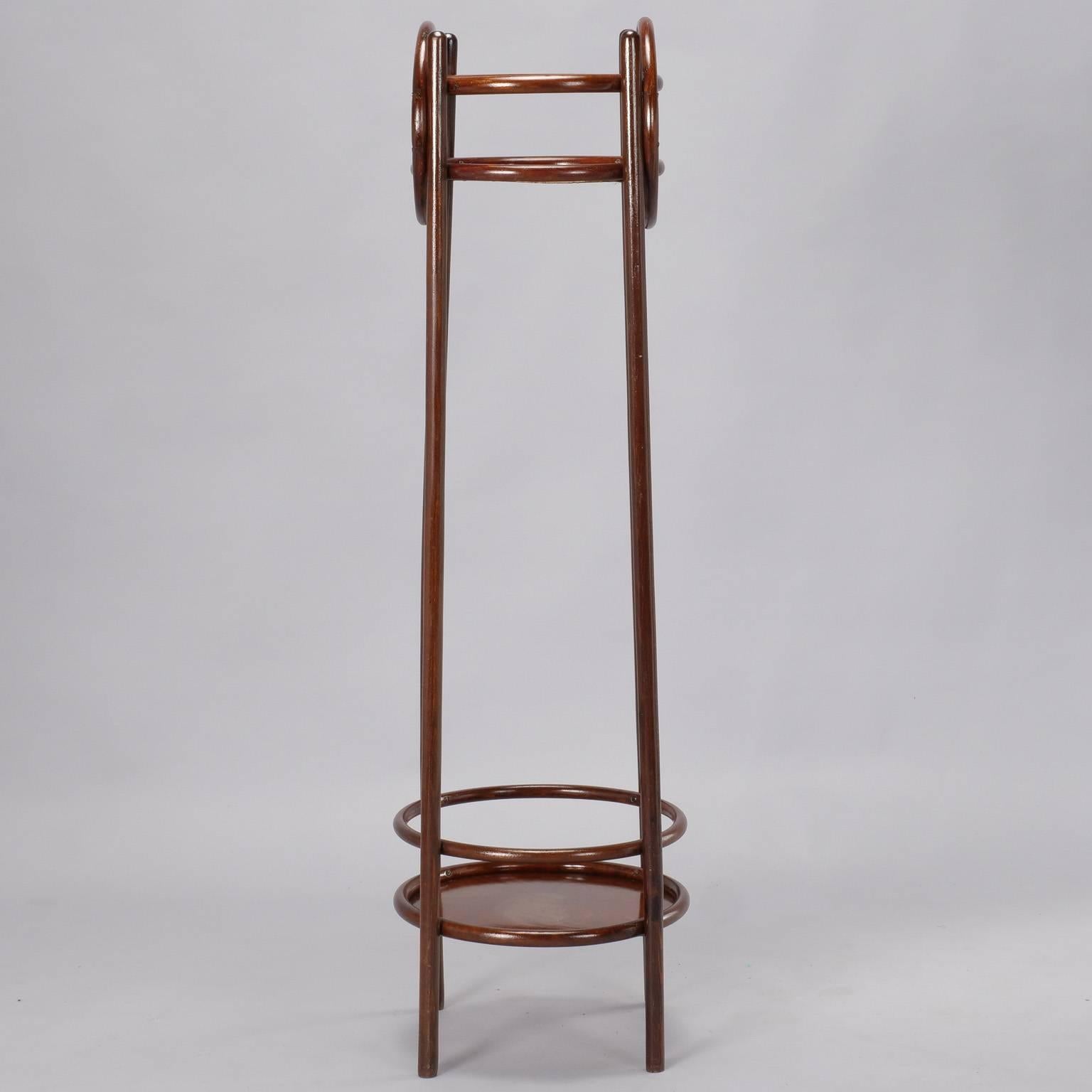 Tall bentwood plant stand has four dark polished wood legs with lower and upper shelves highlighted by decorative circular embellishments on sides, circa 1930s.