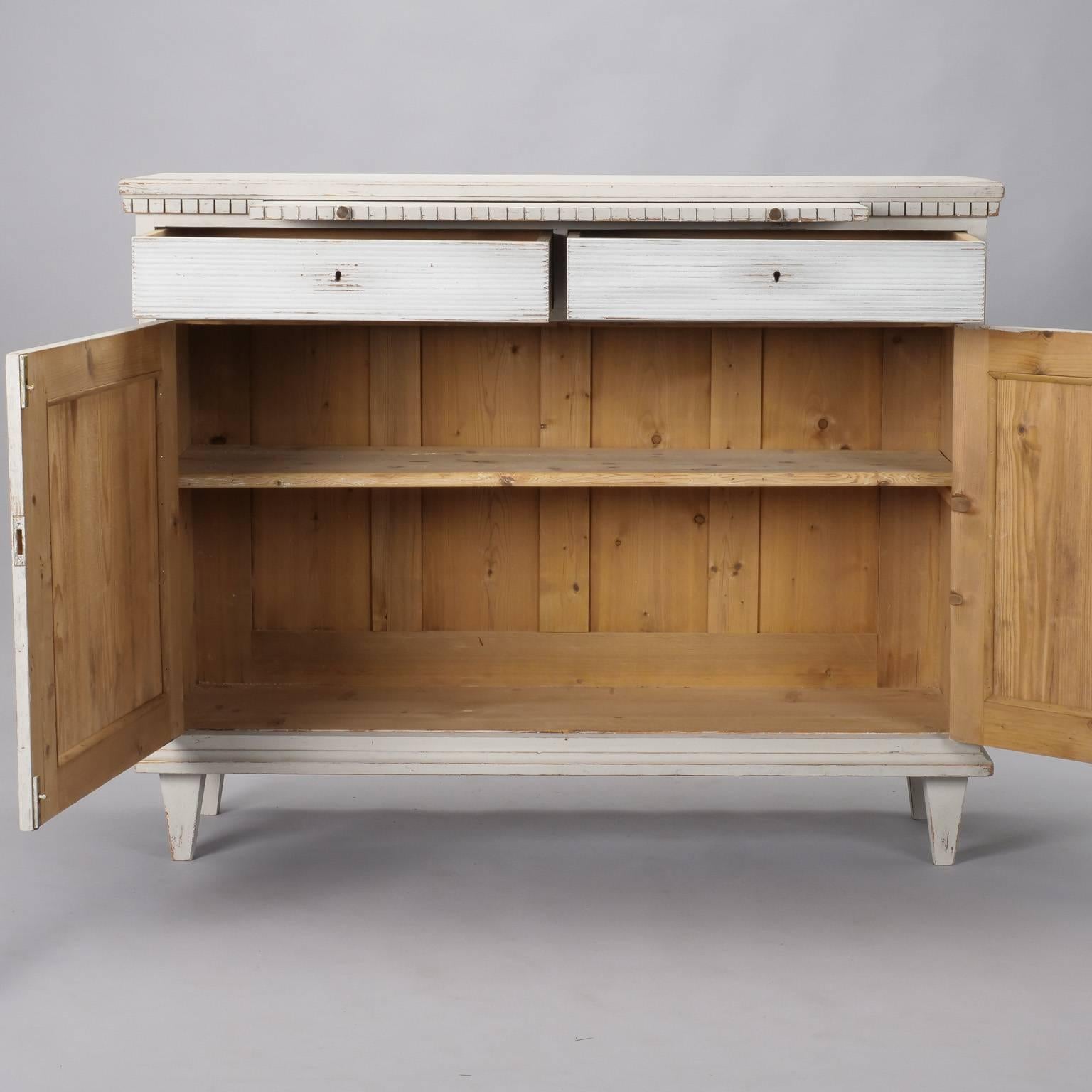 Swedish cabinet is painted in ecru with contrasting white diamond panels and drawer fronts and carved details. Two locking drawers over hinged door locking cabinet feature ridged texture decorative diamond fronts. Internal single shelf. Above the