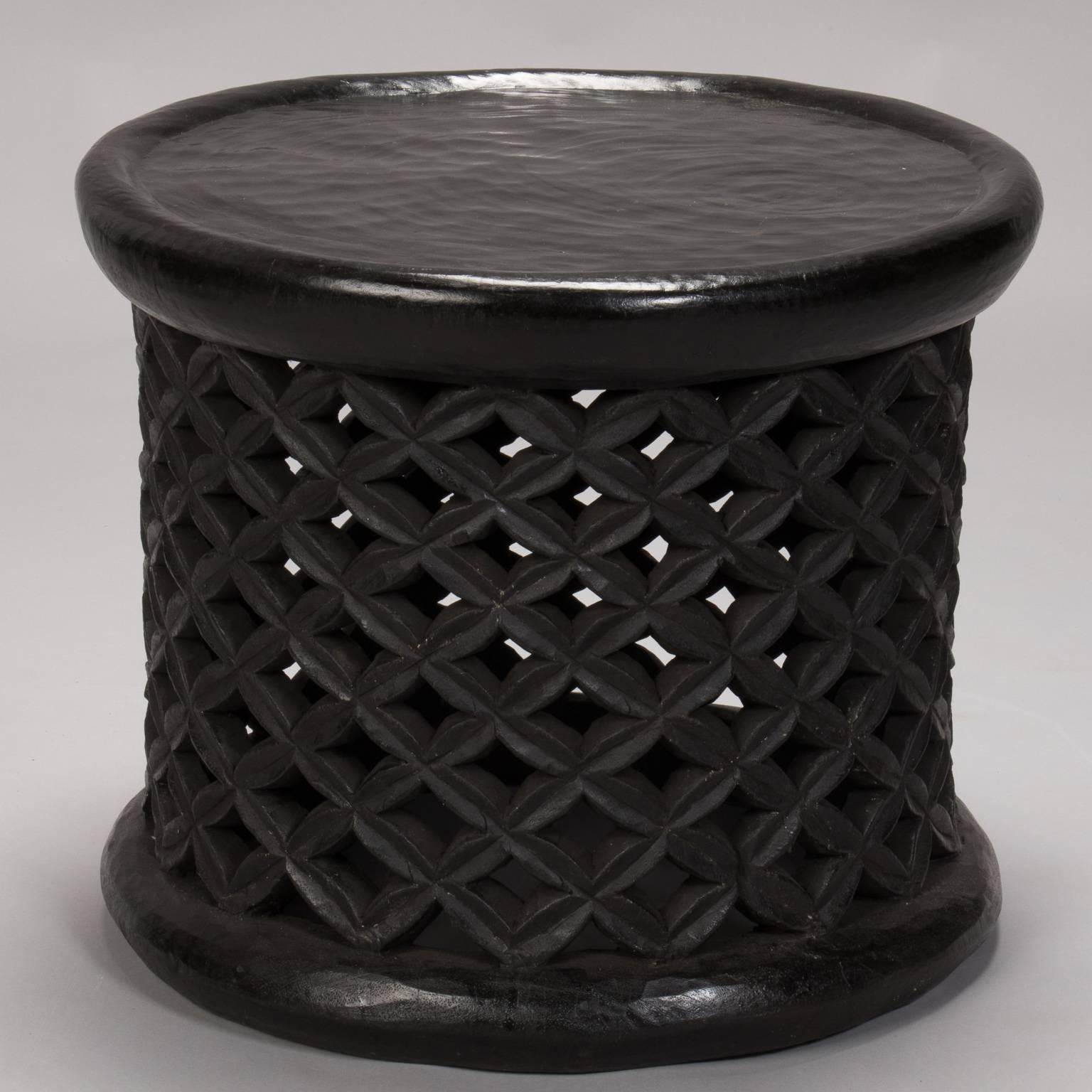 Dark stained hand-carved wooden table or stool from Bameleke people in Cameroon has a round top and base with open work grid pattern on the sides, circa 1960s. Other similar stools or tables available in slightly different sizes/styles also
