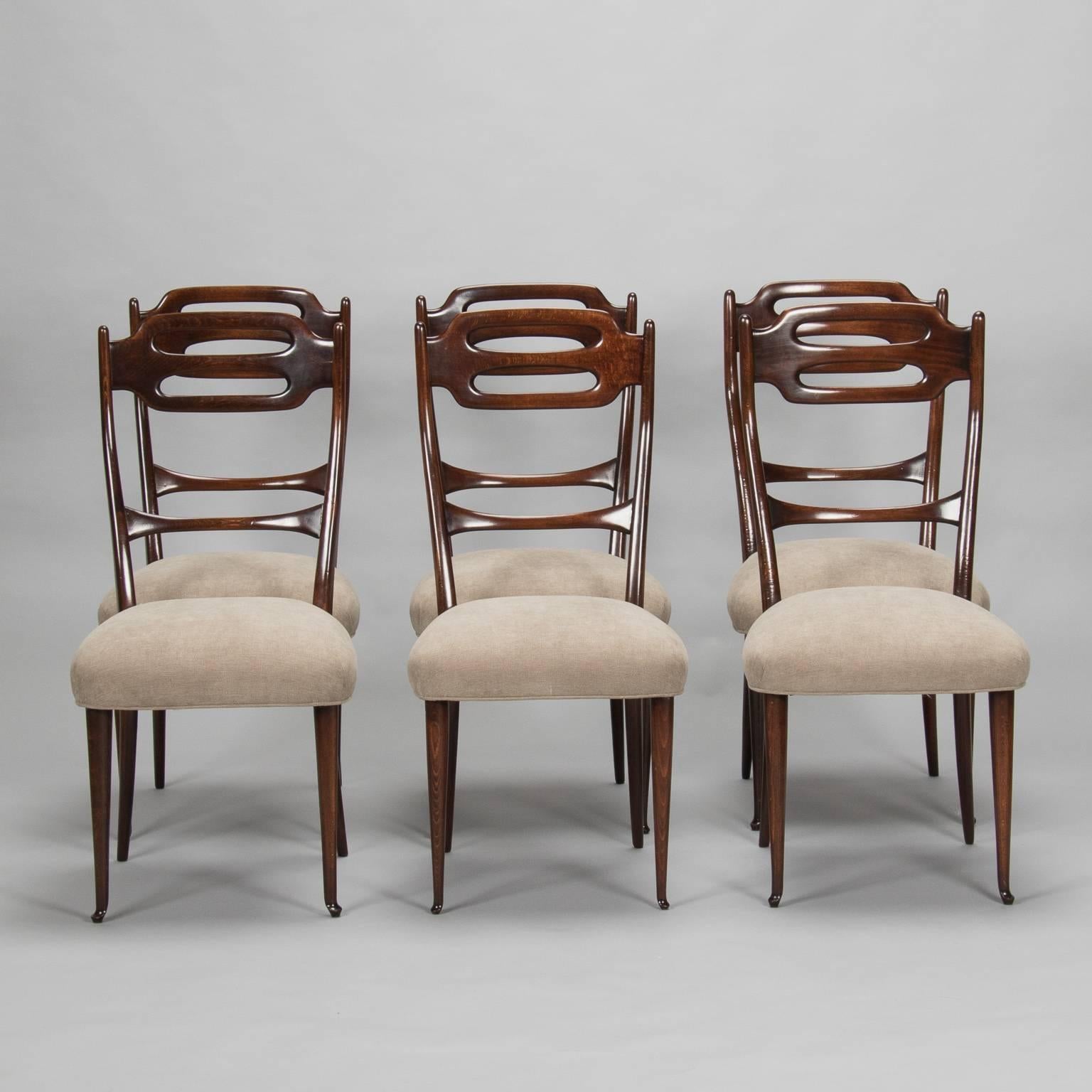 Found in Italy, this set of circa 1950s twelve walnut frame chairs are stained dark with a polished finish. Slender, tapered rails on chair backs and legs add to the sleek, elegant Mid-Century styling. Newly constructed seats are covered in a