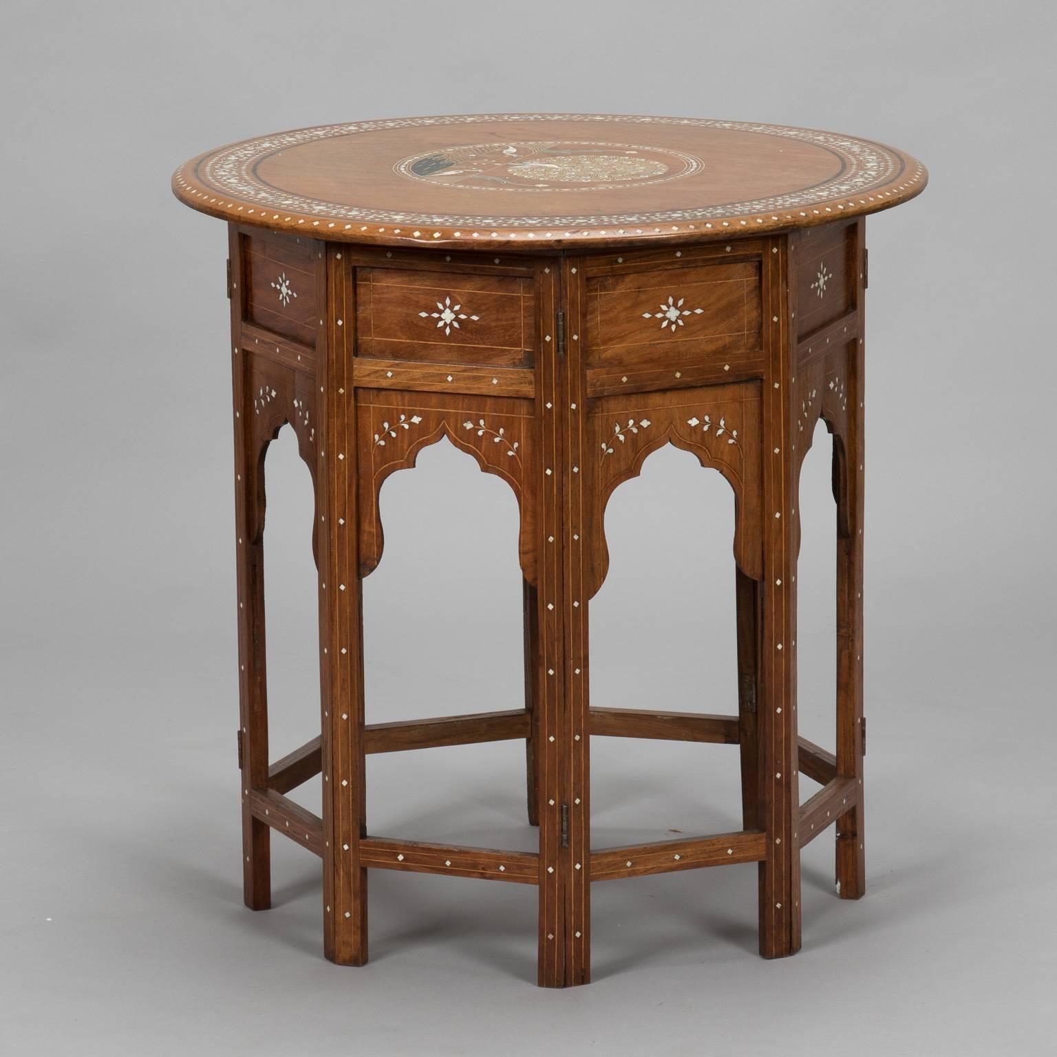 Small Indian made side table has hinged based with removable top which makes it easy to ship and store, circa 1950s. Wood has intricate, finely rendered bone and wood inlay design of peacocks, vines and borders.