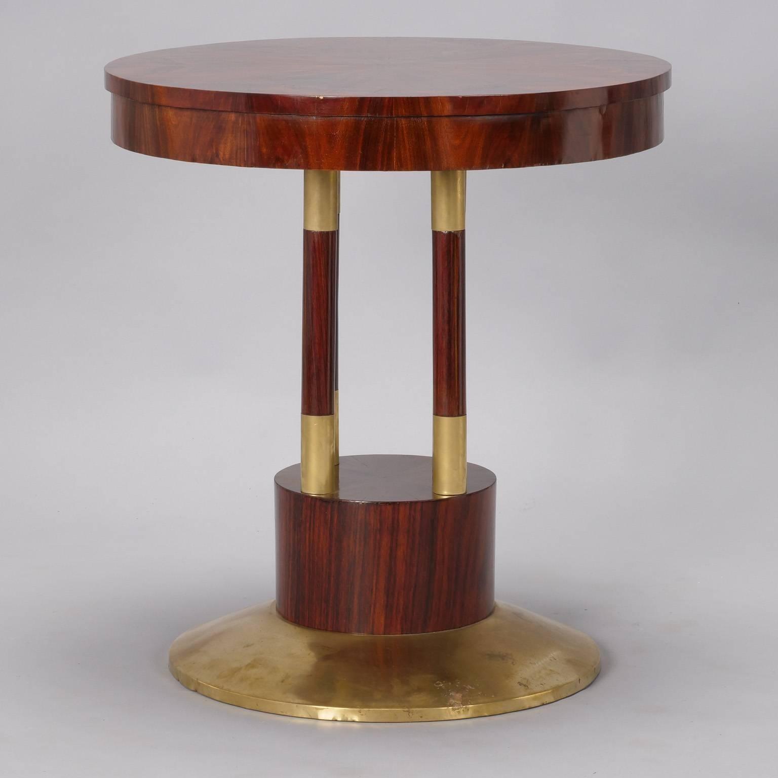 Round pedestal center table has solid brass base and beautifully grained rosewood top, circa 1910. Four support columns trimmed in brass.