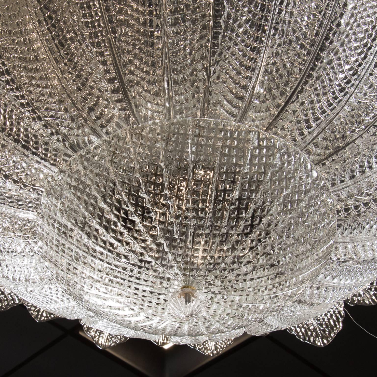 Large Barovier & Toso fixture measure is 40” in diameter with handblown centre bowl surrounded by curved clear glass feather or leaf pieces that give the fixture a flower-like form, circa 2010. Fixture has a total of nine full size sockets. Fixture