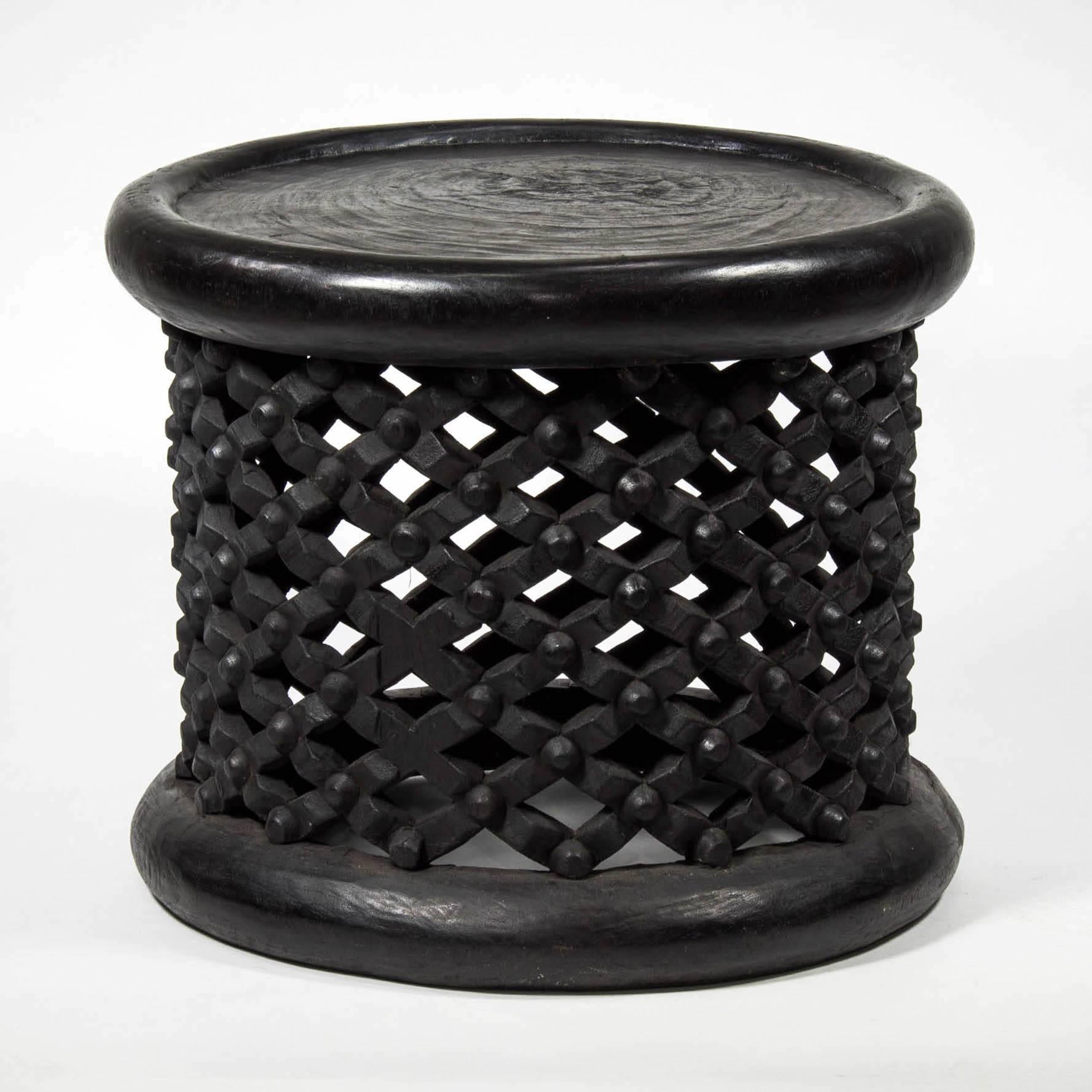 Handmade wood table from Cameroon is dark stained wood with round tabletop and carved lattice/grid pattern. Can be used as a side table or stool. Other similar pieces with slight variations in size/design available at the time of this posting.