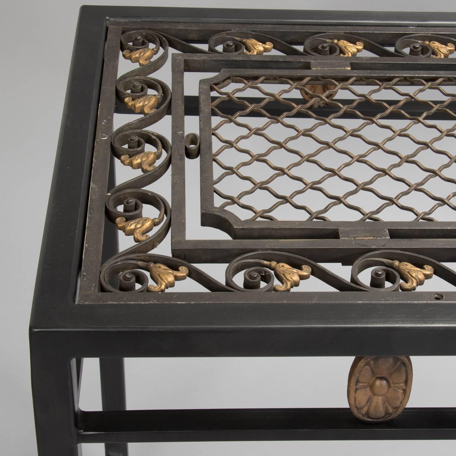 Decorative French iron fragment, circa 1930s is the top of this custom-made console. Protected with a glass top, the fer forge piece is welded to a black iron base with decorative gilded medallions on the apron. One of a kind piece.