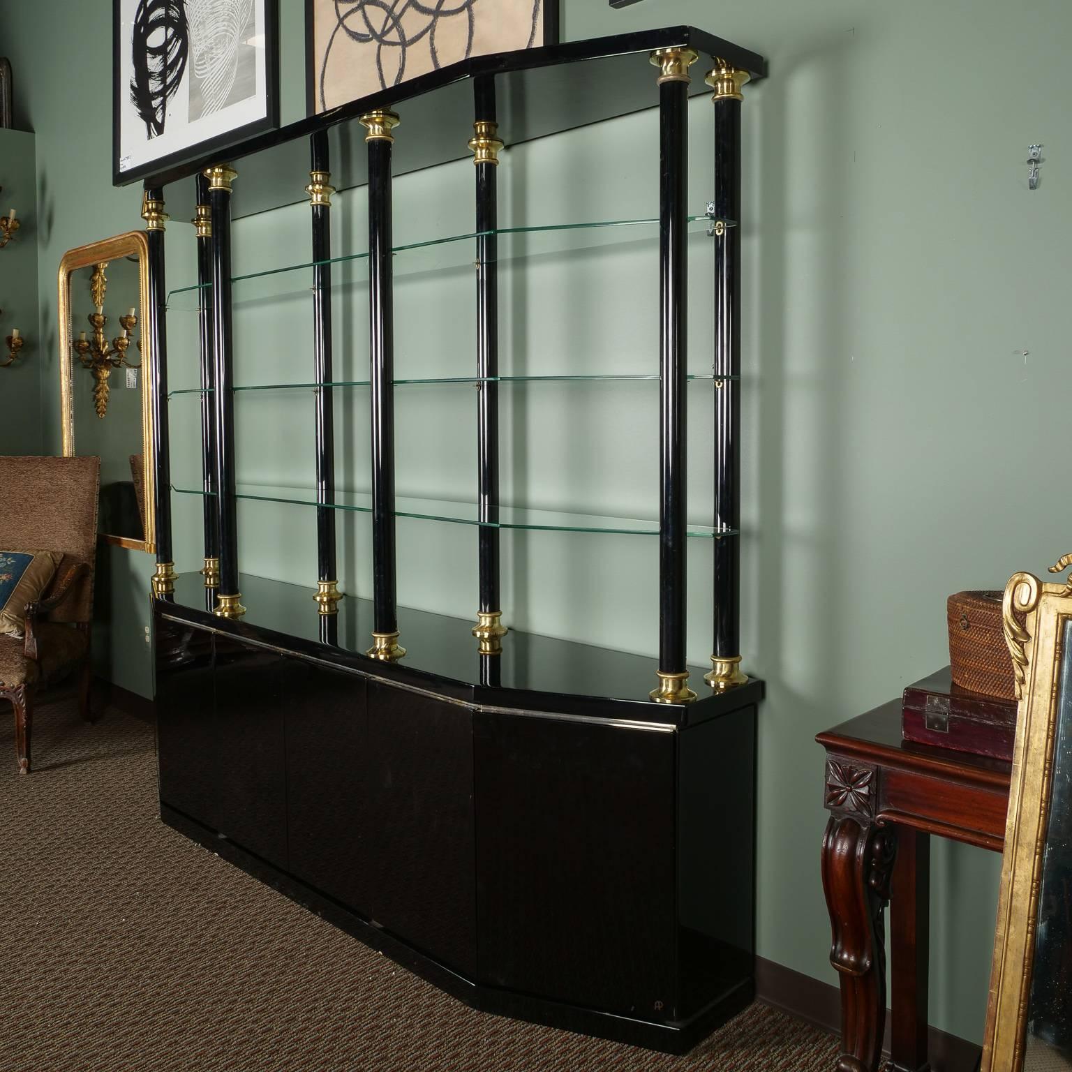 Italian display unit in black lacquered wood with glass shelves and brass accents, circa 1970s. Generously sized lower cabinet has hinged doors with single internal shelf in each section. Surface of cabinet features eight brass trimmed column