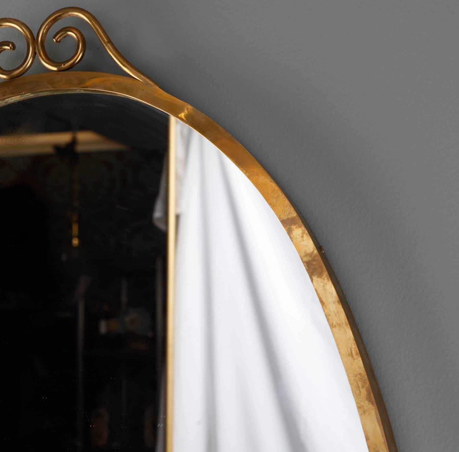 Tall oval mirror with brass frame and delicate scrolled crest. Found in France, believed to be Italian dating from late 1950s/early 1960s.
