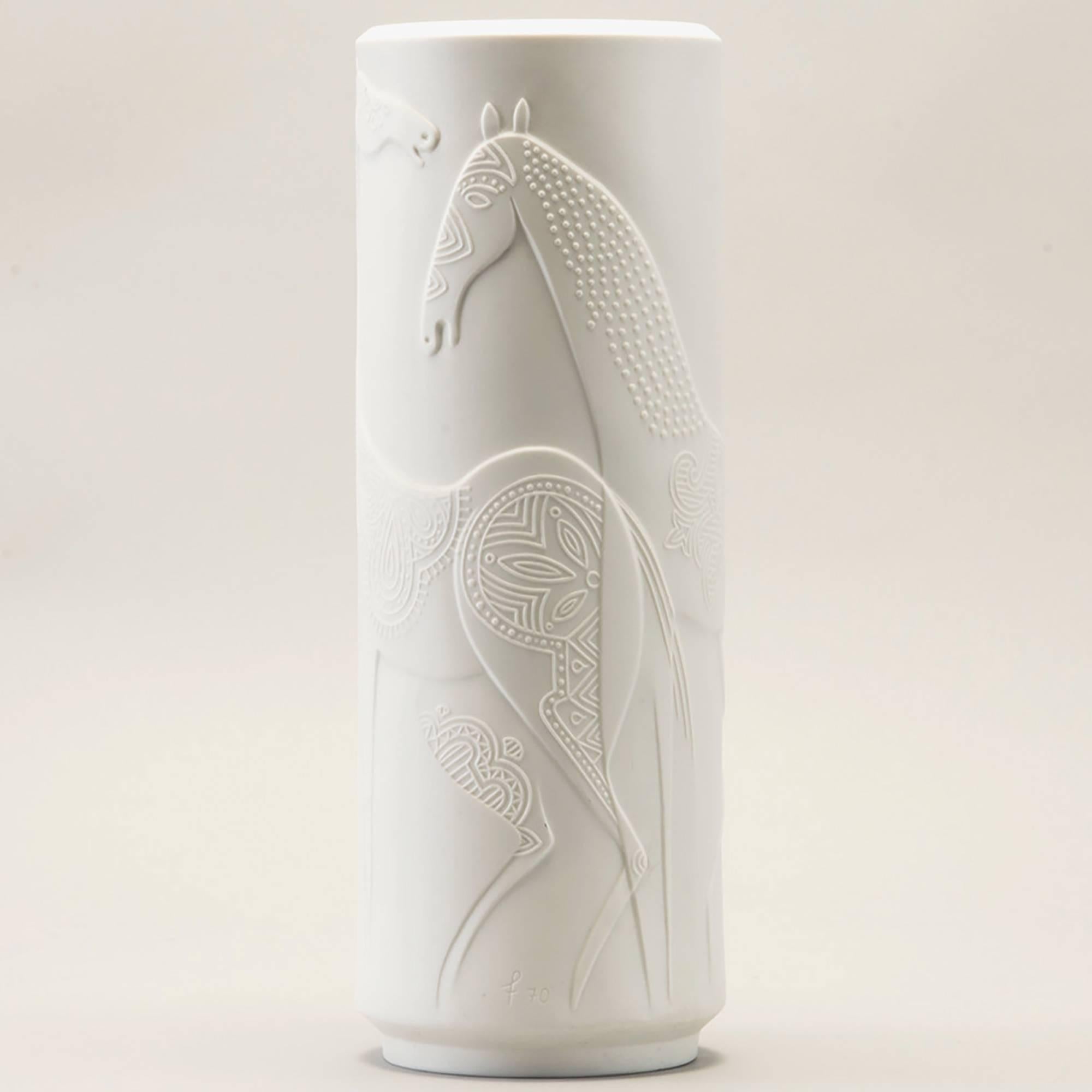 Circa 1970s tall white porcelain vase designed by Cuno Fischer for German maker Hutschenreuther with a design of stylized horses in relief. Round vase is over 13” tall and has matte finish outside and glazed interior. Marks include artist’s