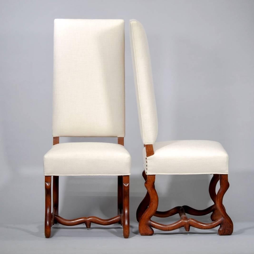 Set of eight classic Os de Mouton French dining chairs, circa 1920s. Carved dark wood frames, with each chair seat and back professionally rebuilt and newly upholstered in a neutral, off-white linen weave cotton blend fabric. All chairs are armless.