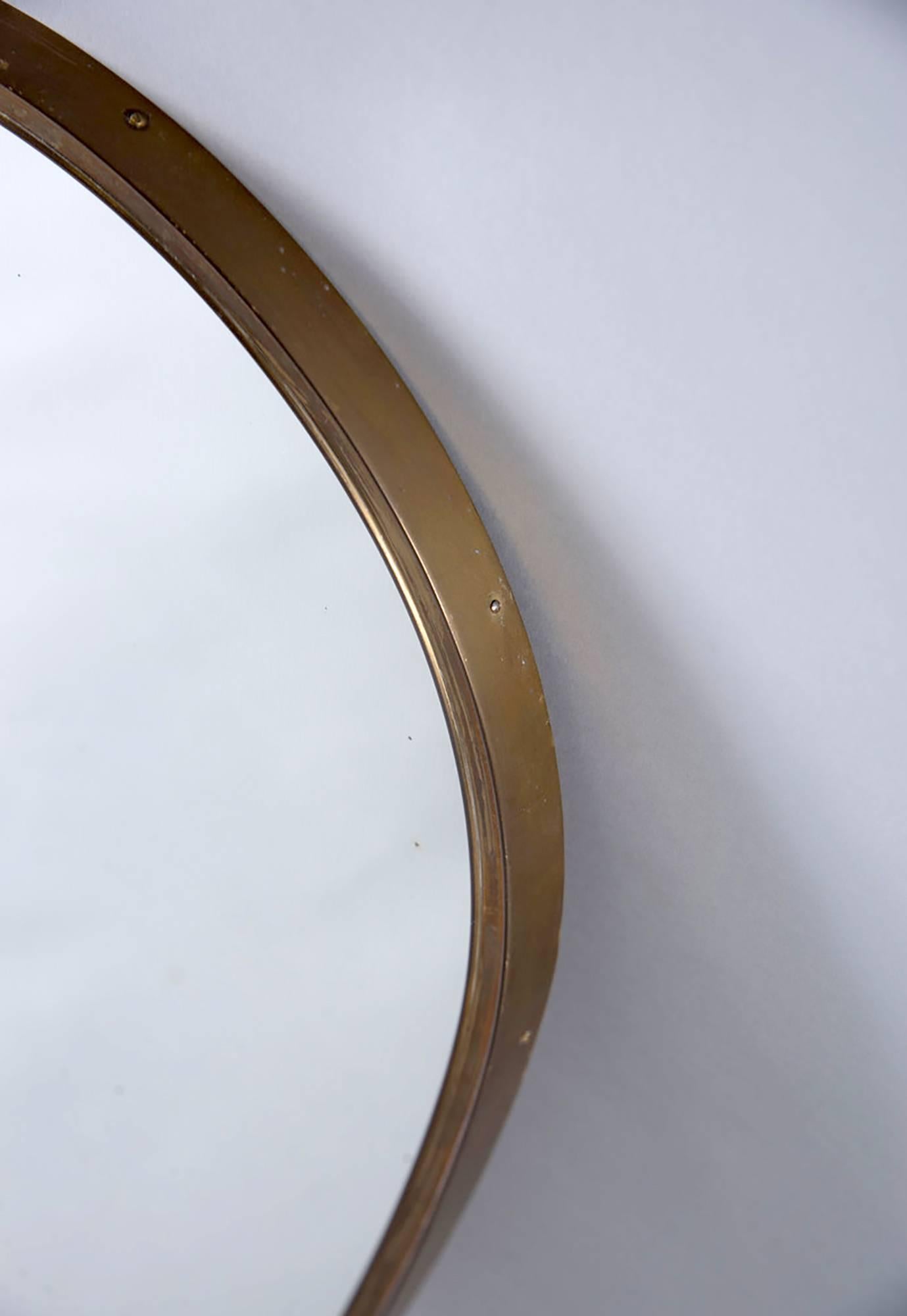 German mirror has a wooden back and Minimalist ovoid brass frame in the style of Gio Ponti, circa 1970s.