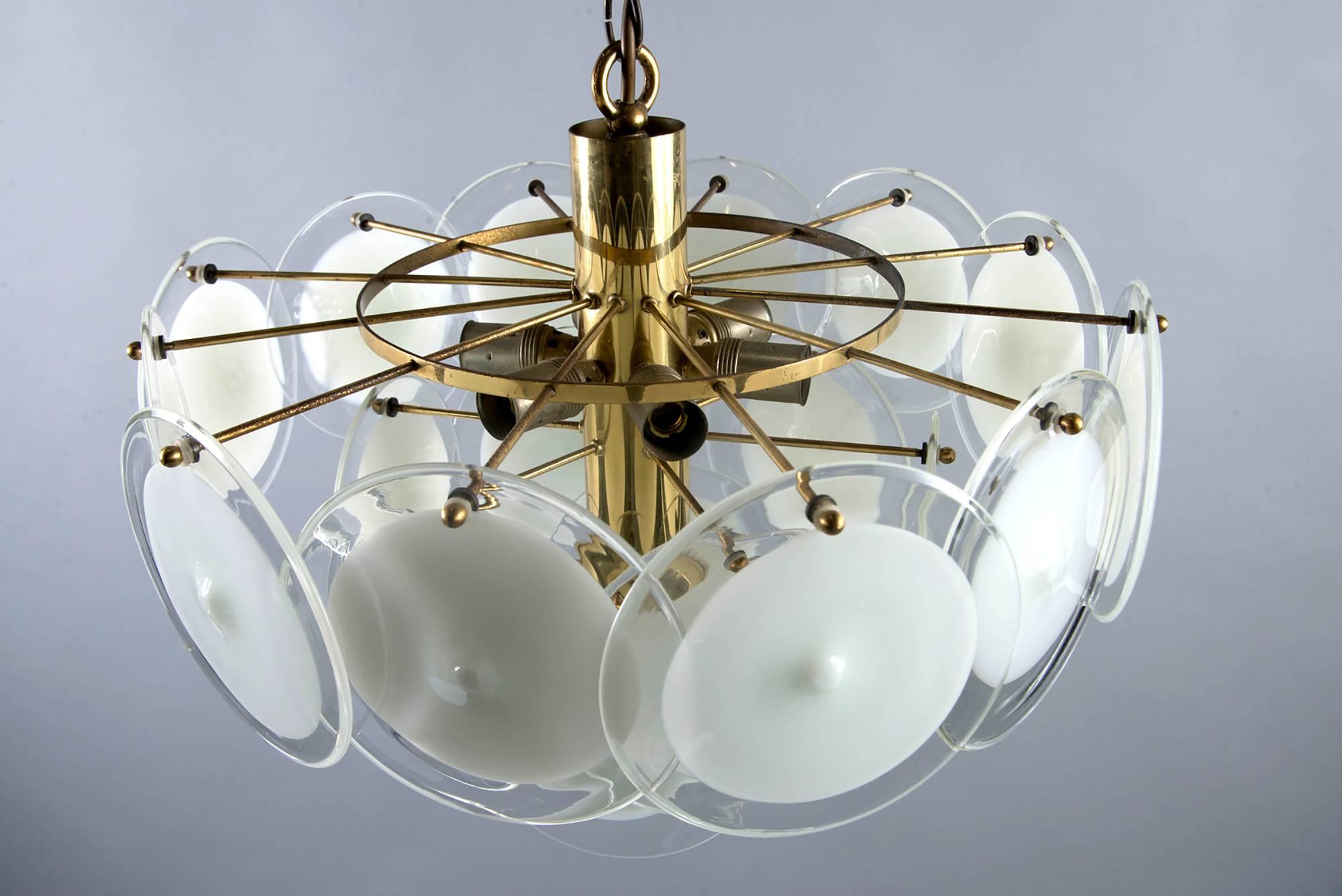 Murano glass chandelier manufactured by Vistosi features a brass-plated metal base with three tiers of suspended glass disks, circa 1960s. Round glass elements are opaque white at the center with clear edges. Chandelier has been rewired for US